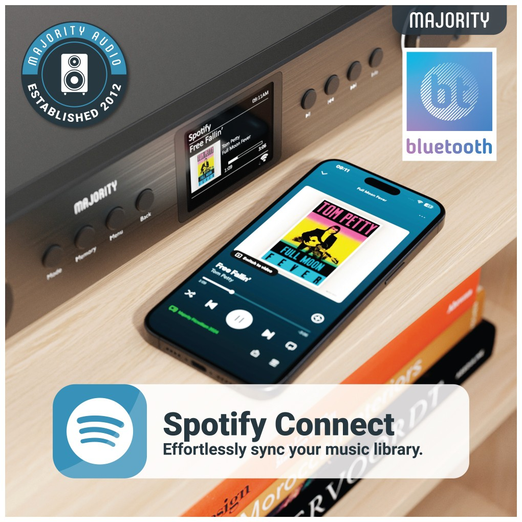 Une radio noire avec un écran diffusant une application musicale sur une étagère avec un smartphone.