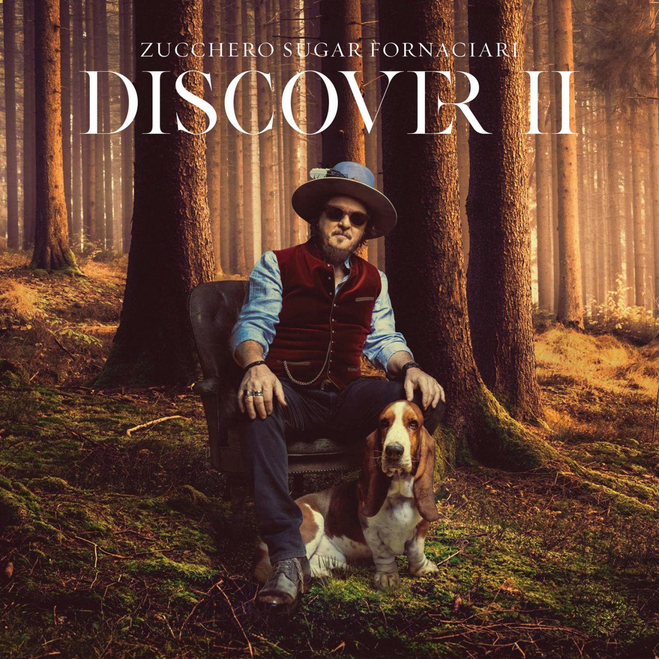 Egy férfi egy székben ül egy erdőben egy kutyával. A tetején a szöveg: "Discover II".