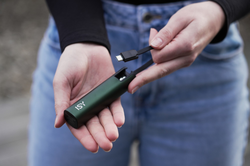 Ręka trzymająca ciemnozielone urządzenie ISY z podłączonym kablem USB-C.