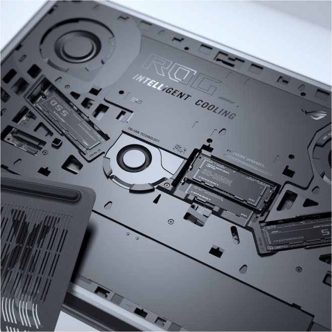Laptop belseje, alkatrészek, SSD-k, hűtőrendszer látható, fehér háttér.