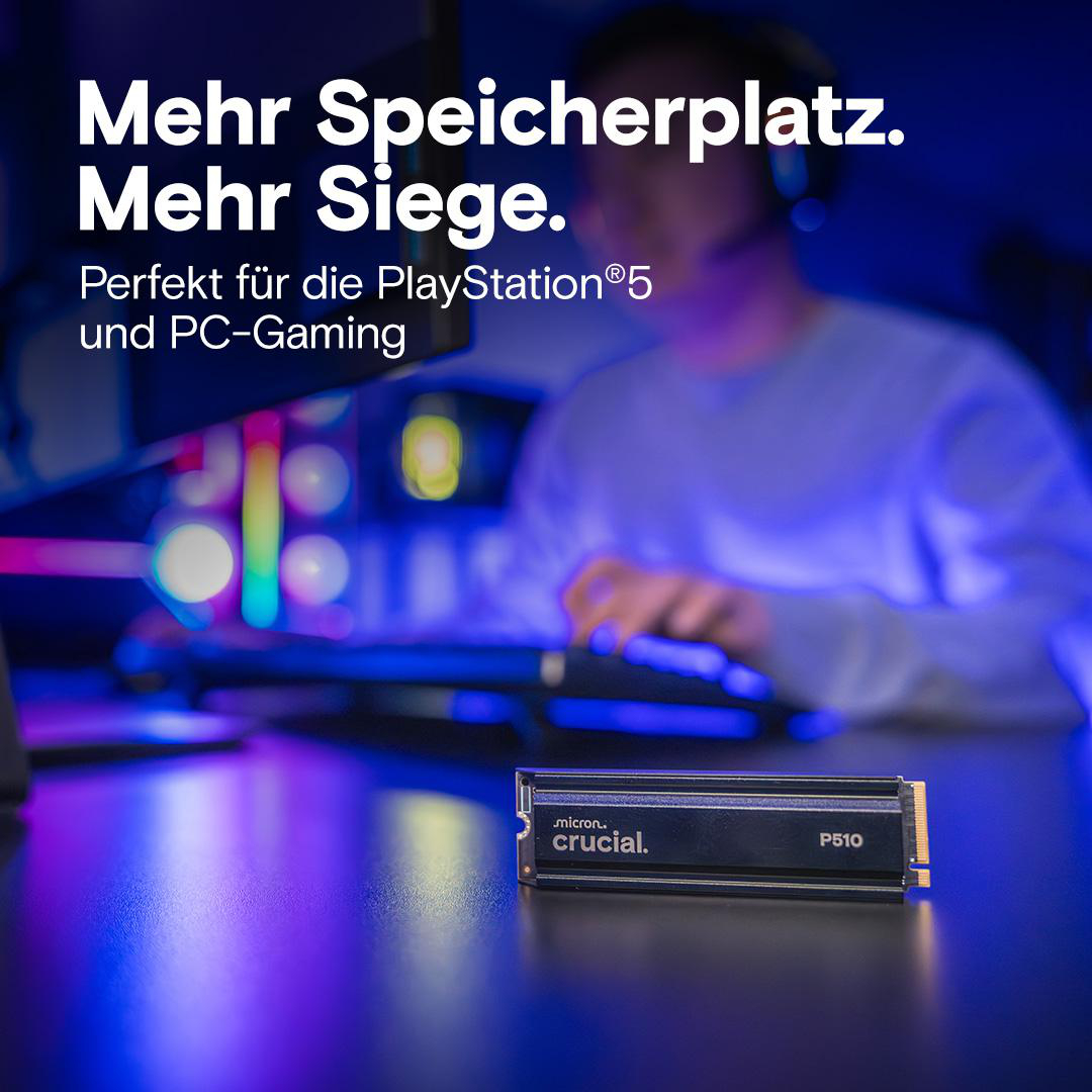 Eine schwarze SSD liegt auf einer dunklen Oberfläche. Im Hintergrund benutzt eine Person einen Computer.