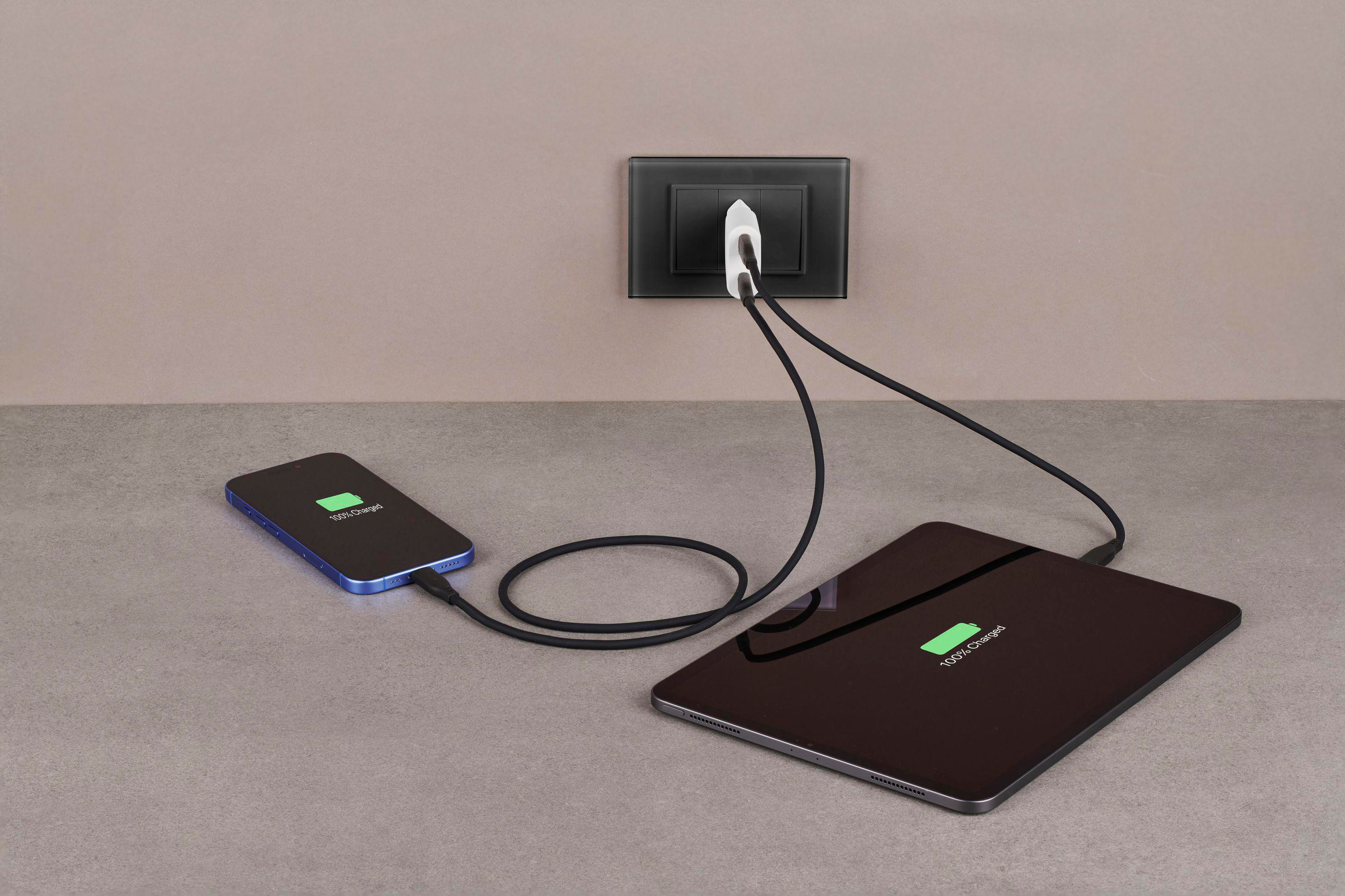 Ein Telefon und ein Tablet laden über ein Ladegerät an einer Steckdose auf.
