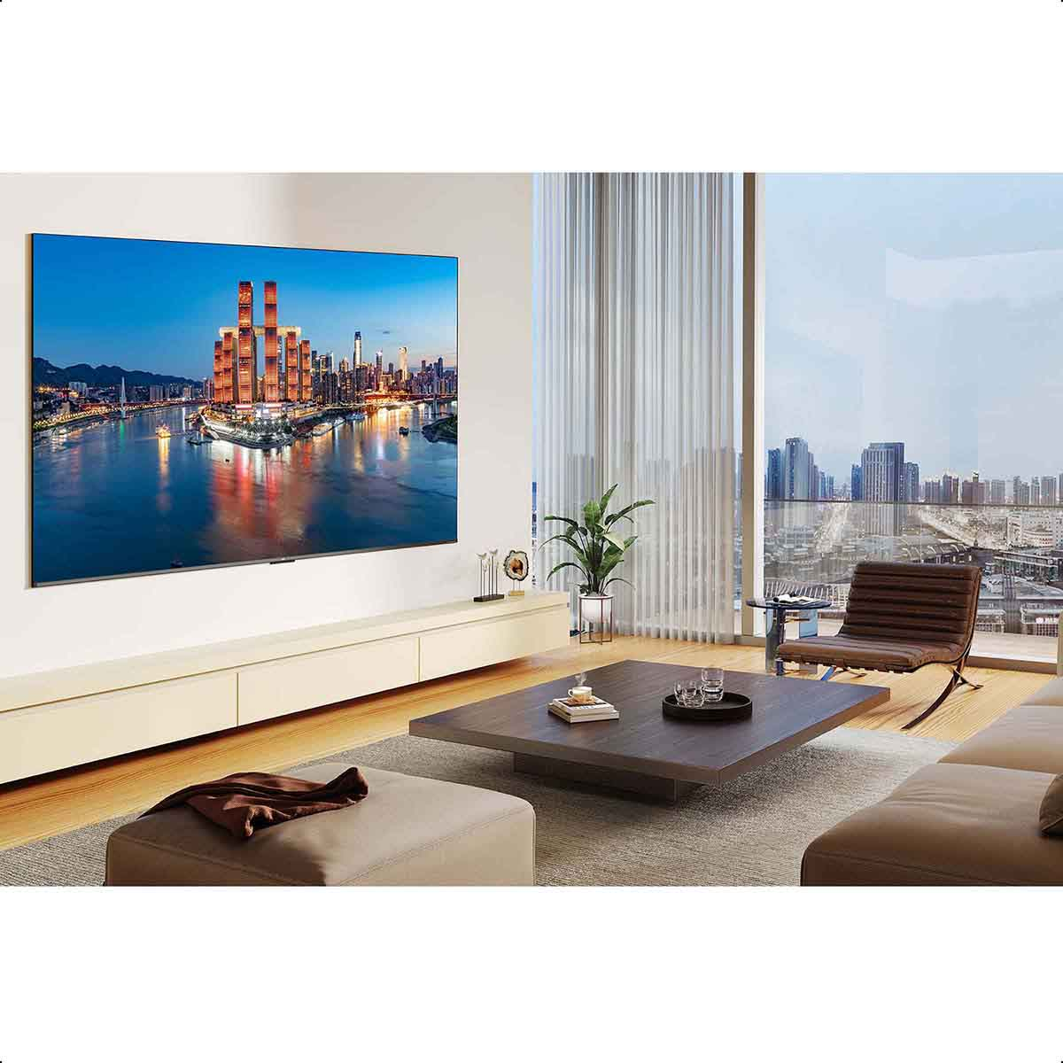 Das Bild zeigt ein Wohnzimmer mit einem Fernseher, der eine Stadtansicht zeigt, und Möbeln, darunter ein weißes Sofa und ein Holztisch.