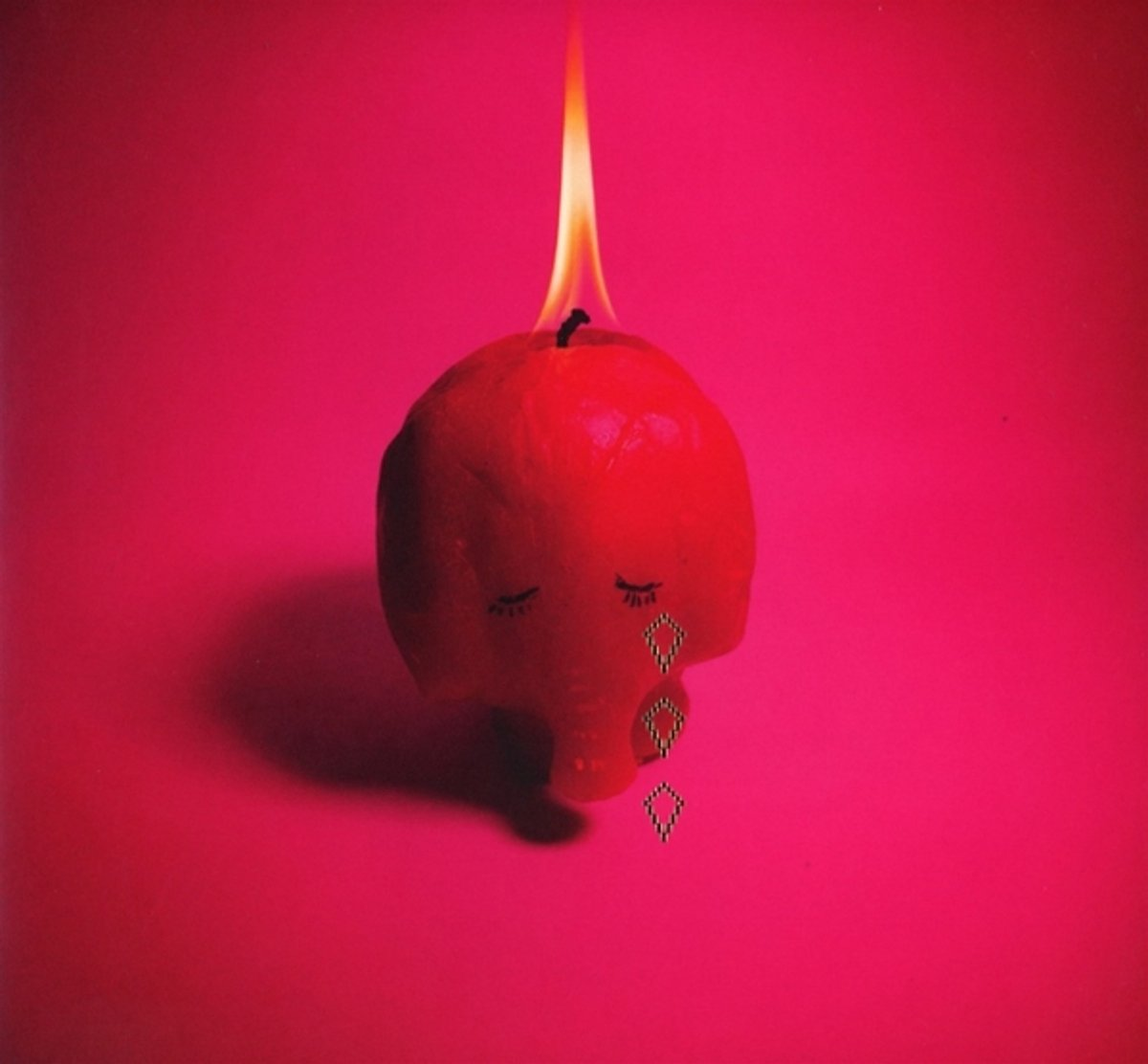 Une bougie en forme de crâne en rouge avec des larmes. La flamme est allumée.