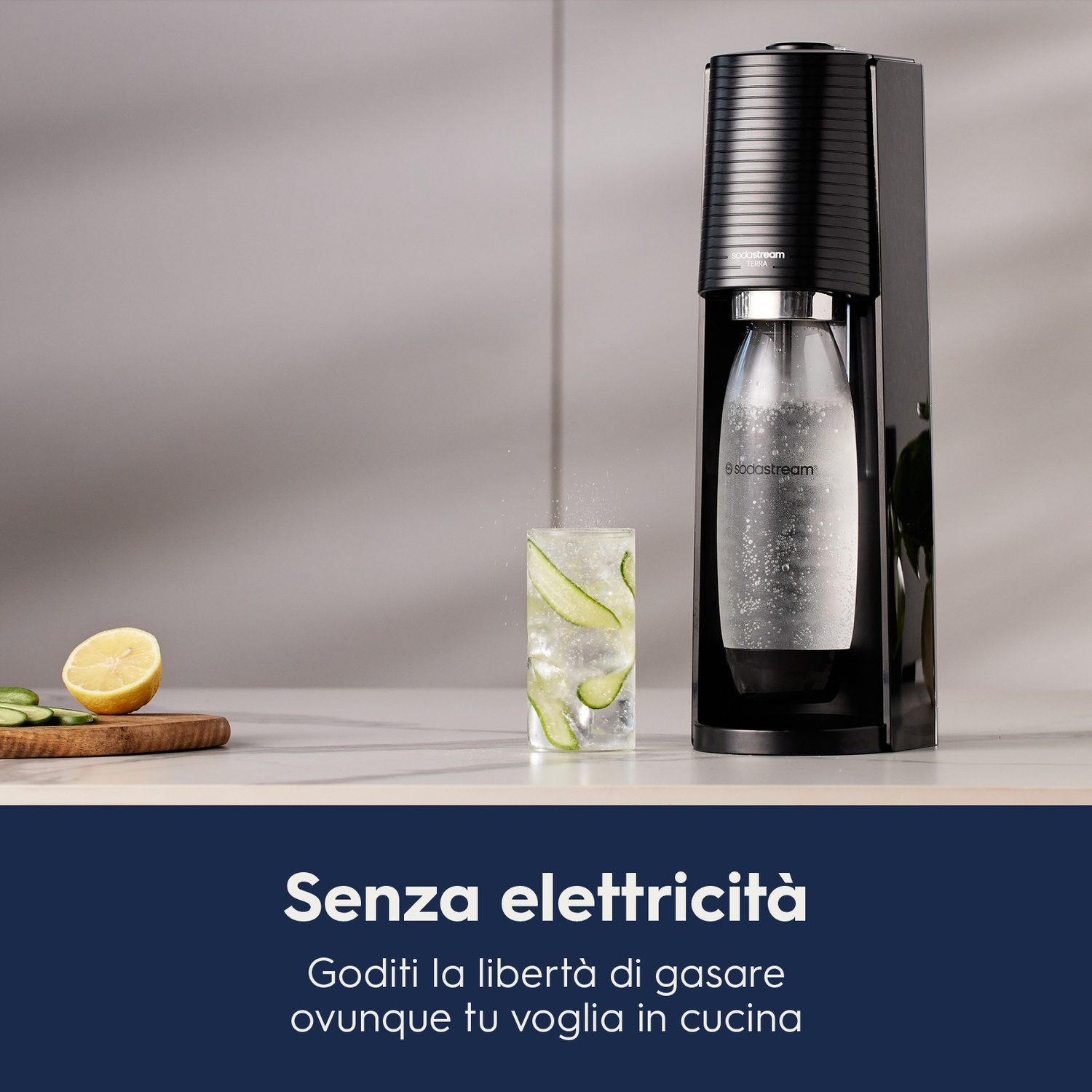 Una macchina SodaStream nera con un bicchiere d'acqua con fette di cetriolo e un limone.