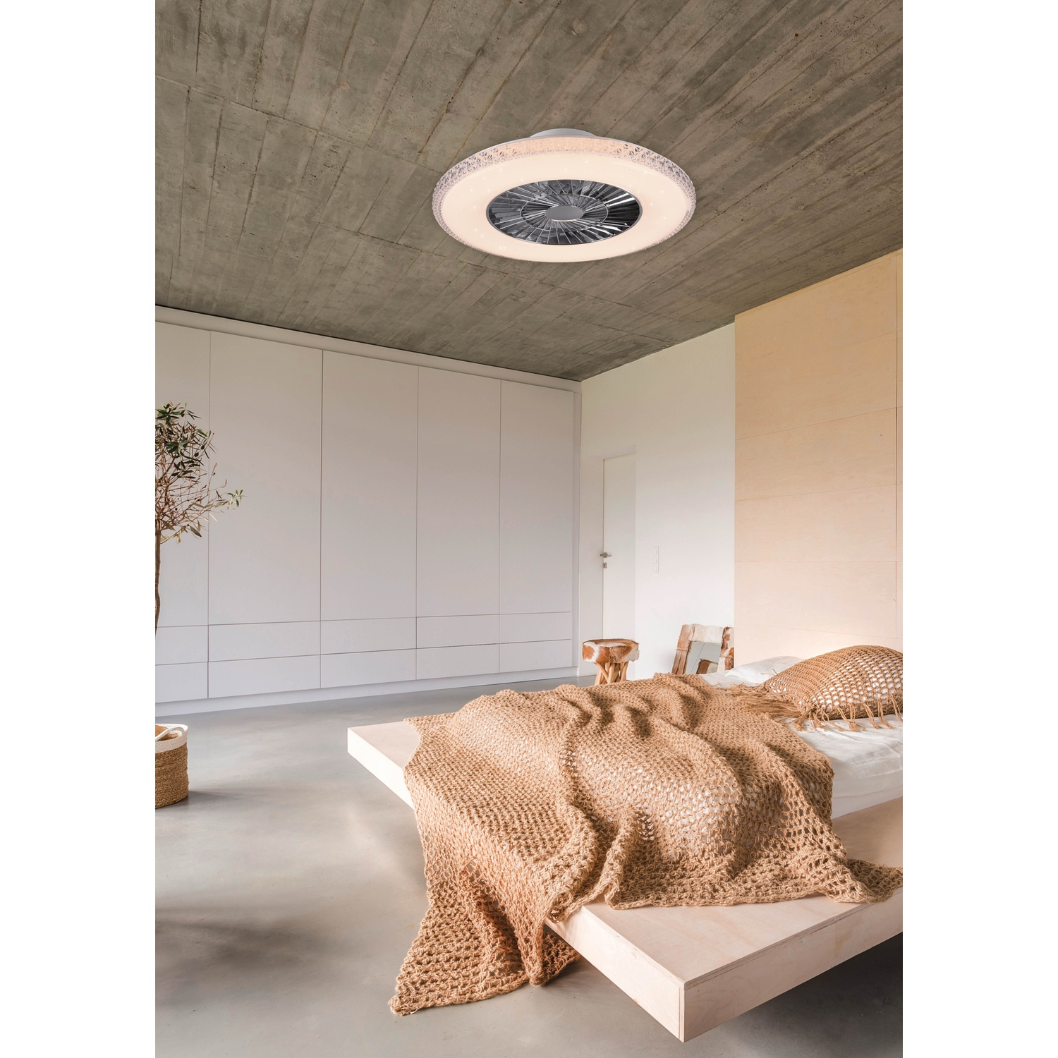 Camera da letto con ventilatore/lampada a soffitto. Letto con coperta beige, armadi bianchi sullo sfondo.