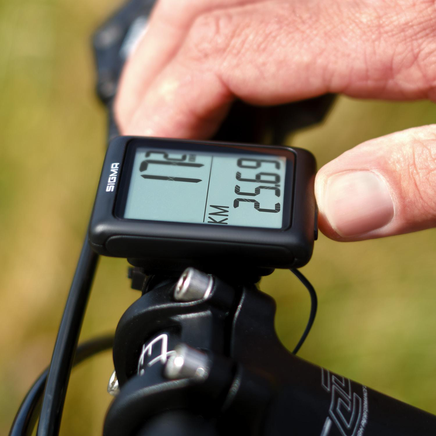 Hand stellt Fahrradcomputer am Fahrrad ein. Geschwindigkeit und Entfernung werden angezeigt.