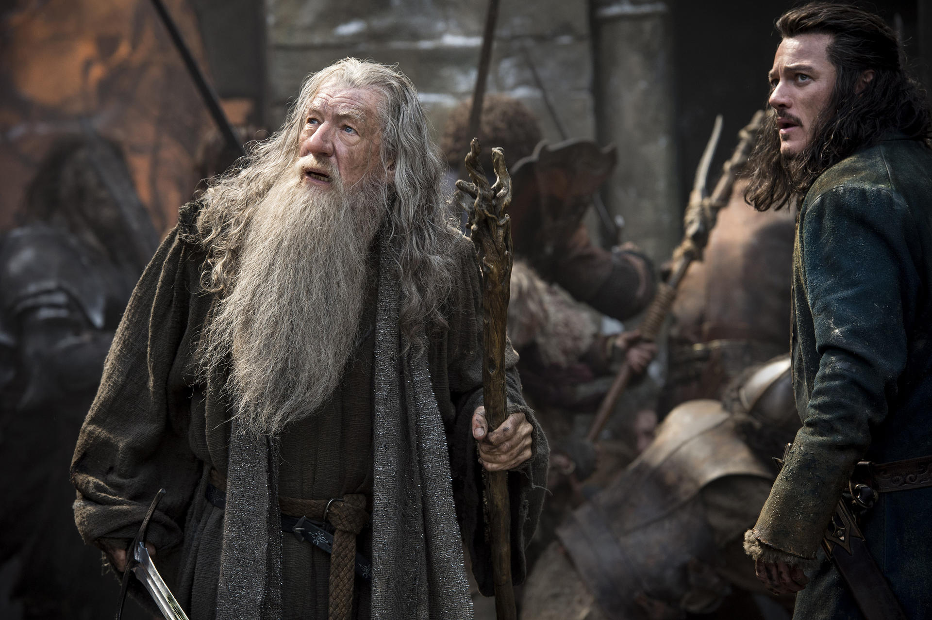 Gandalf und ein anderer Mann schauen sich an. Im Hintergrund sind andere Leute zu sehen.