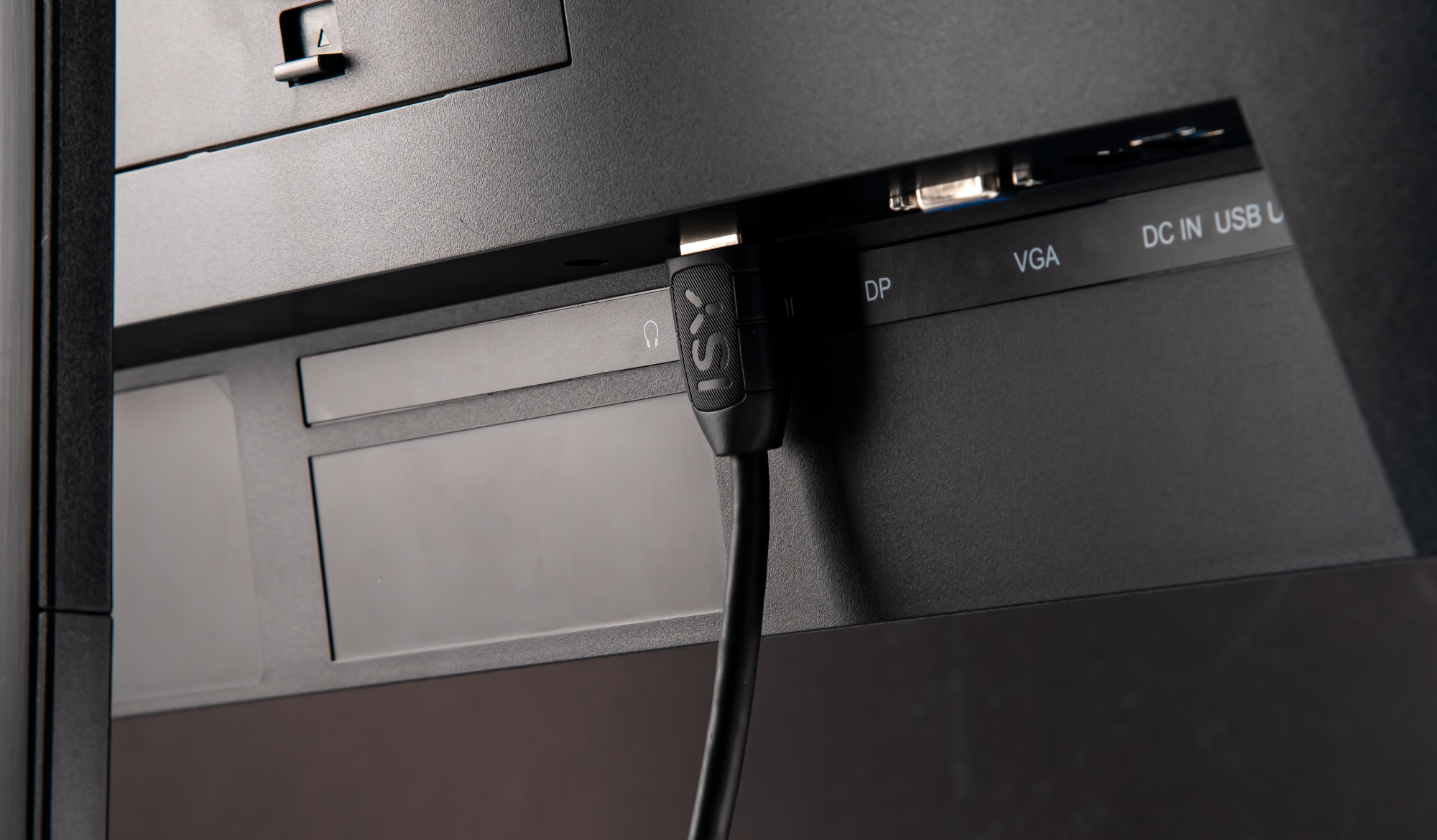 Fekete HDMI kábel egy monitor hátuljához csatlakoztatva, csatlakozókkal.