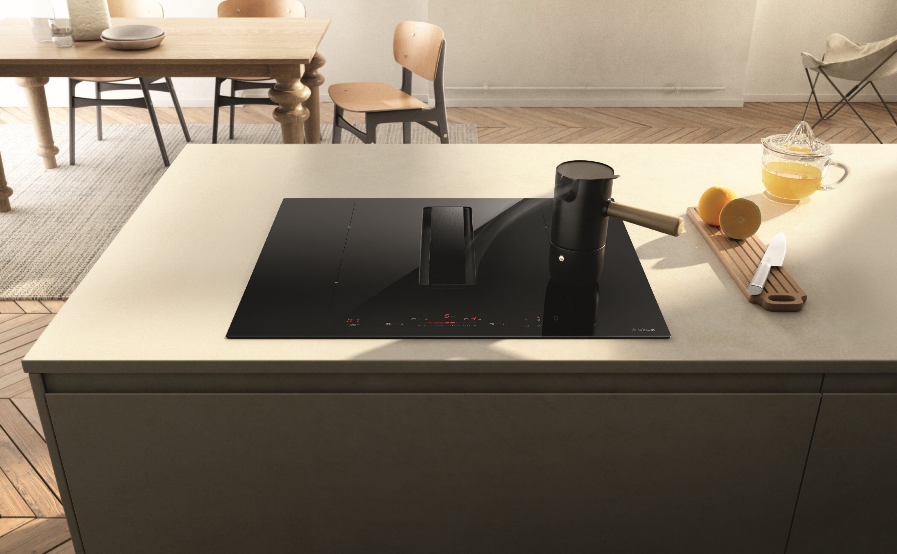 Kuchnia z czarną płytą grzewczą, pomarańczami i ekspresem do kawy. Nowoczesny design i jasna przestrzeń.