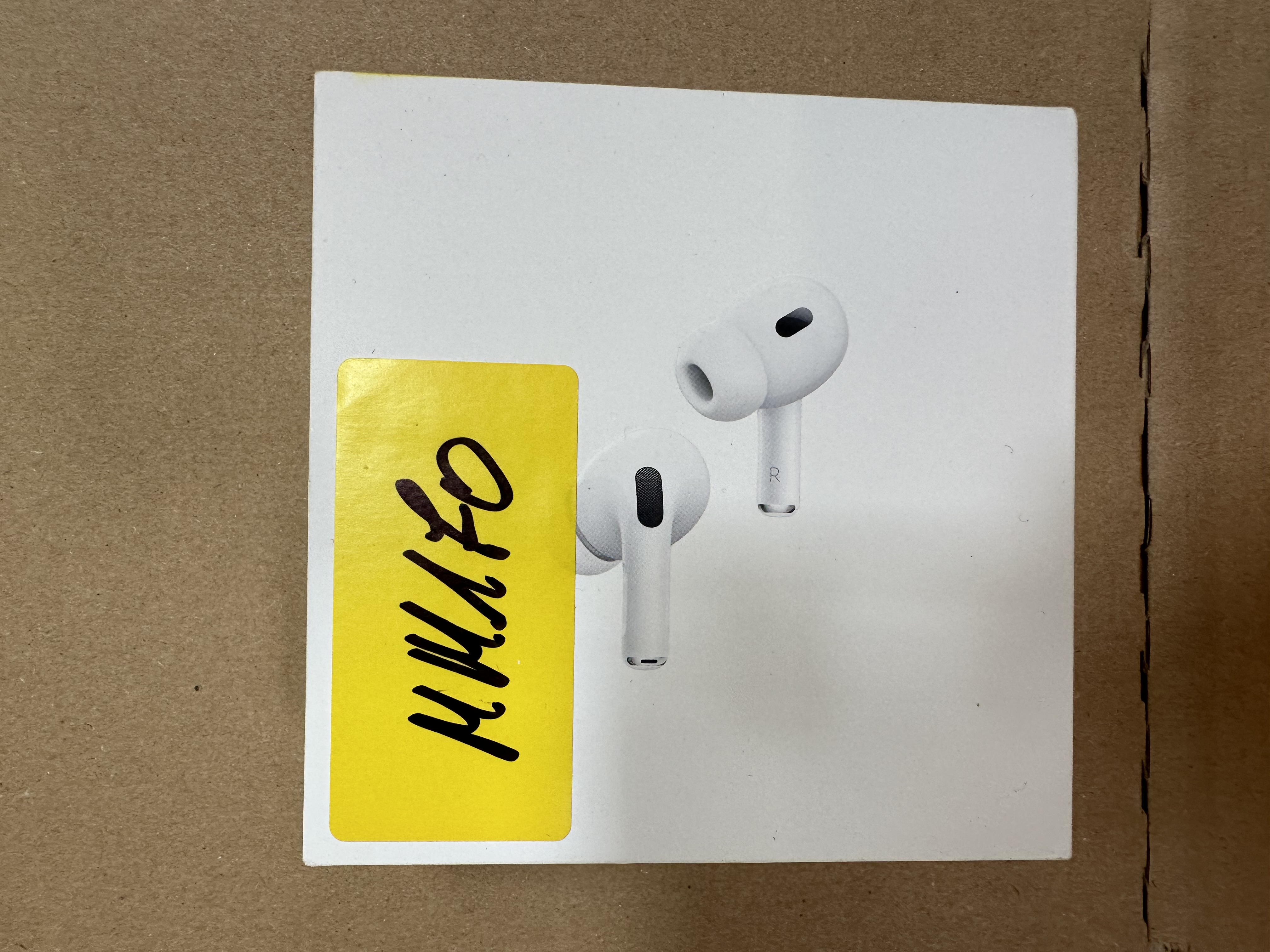 Białe pudełko z AirPods Pro 2 w środku, naklejka z kodem na wierzchu.