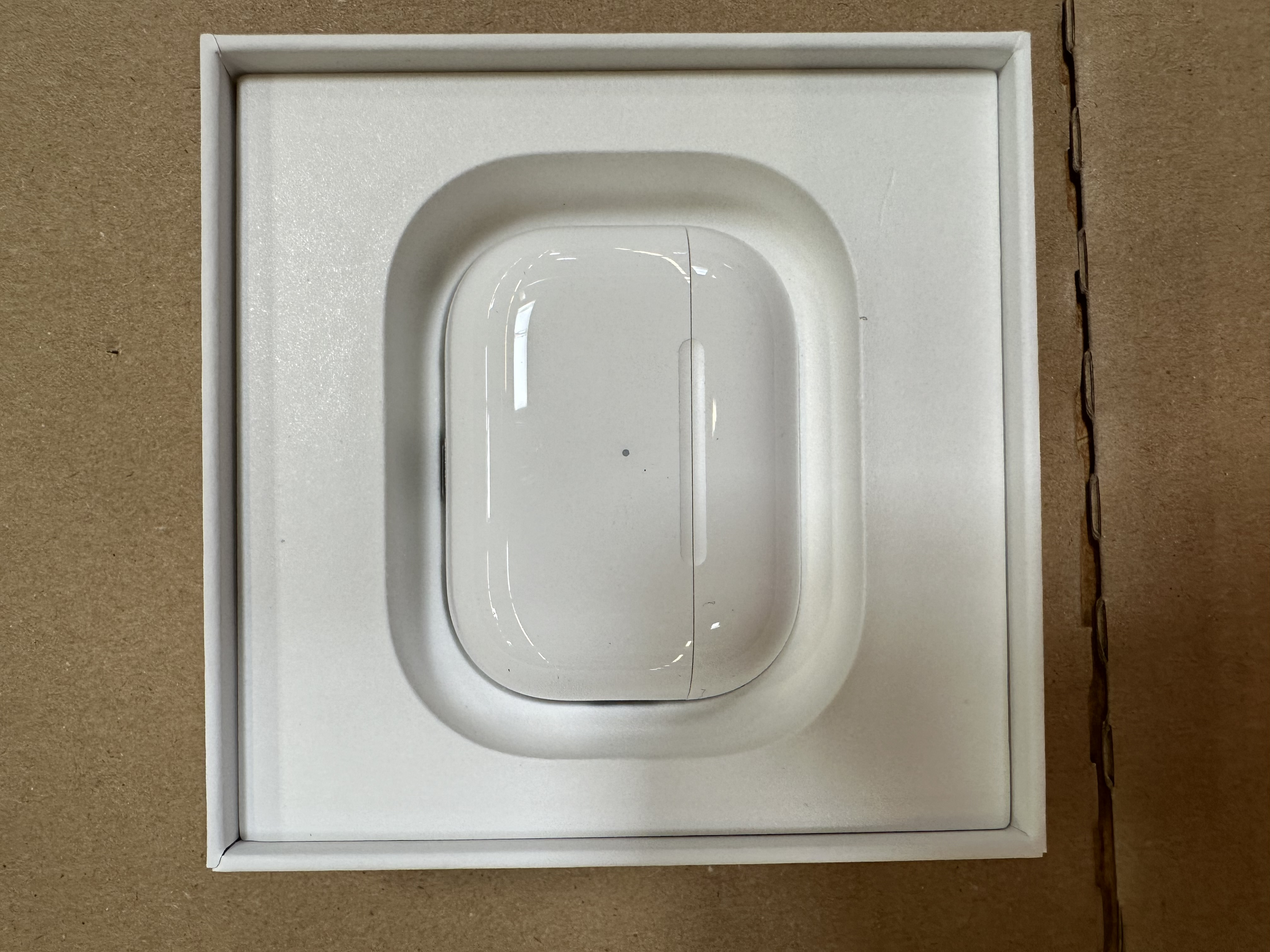 Białe etui AirPods Pro 2, otwarte, na kartonowej powierzchni.