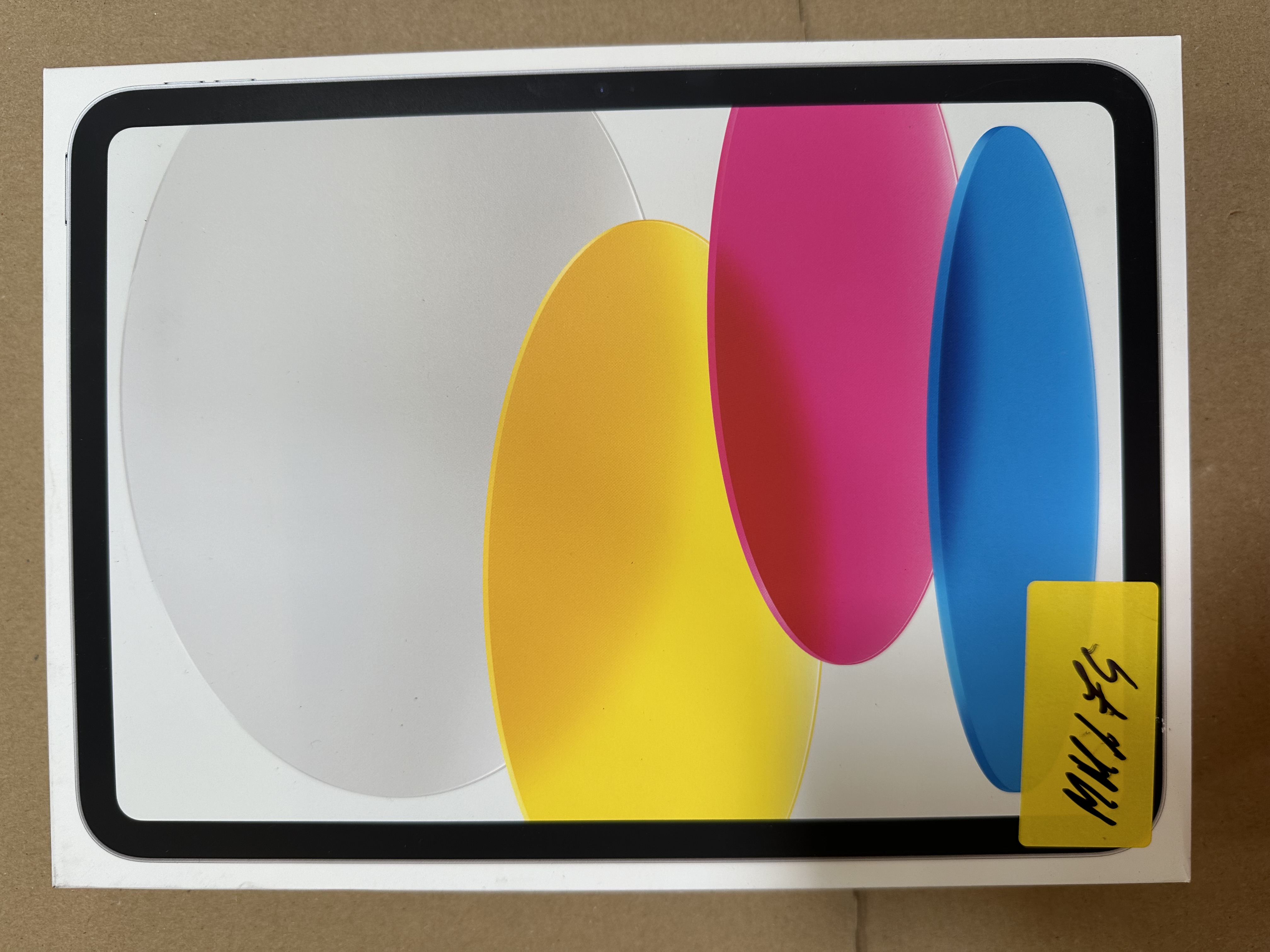 Pudełko tabletu ma białe tło z żółtymi, różowymi i niebieskimi abstrakcyjnymi kształtami.