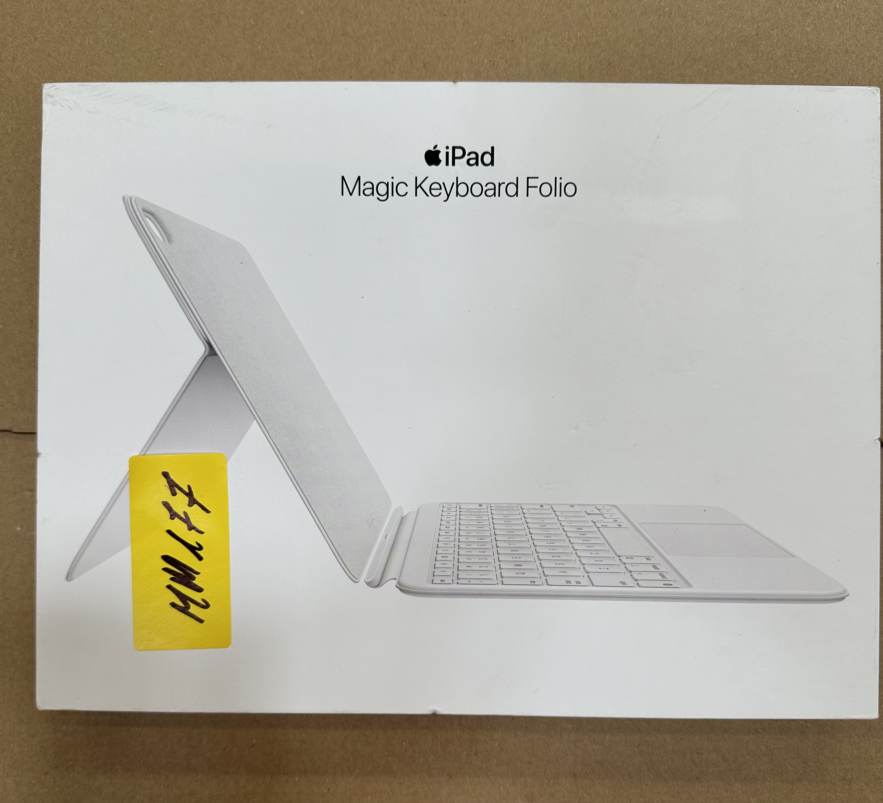 Białe pudełko iPad Magic Keyboard Folio z żółtą naklejką. Widok z boku. Białe tło.
