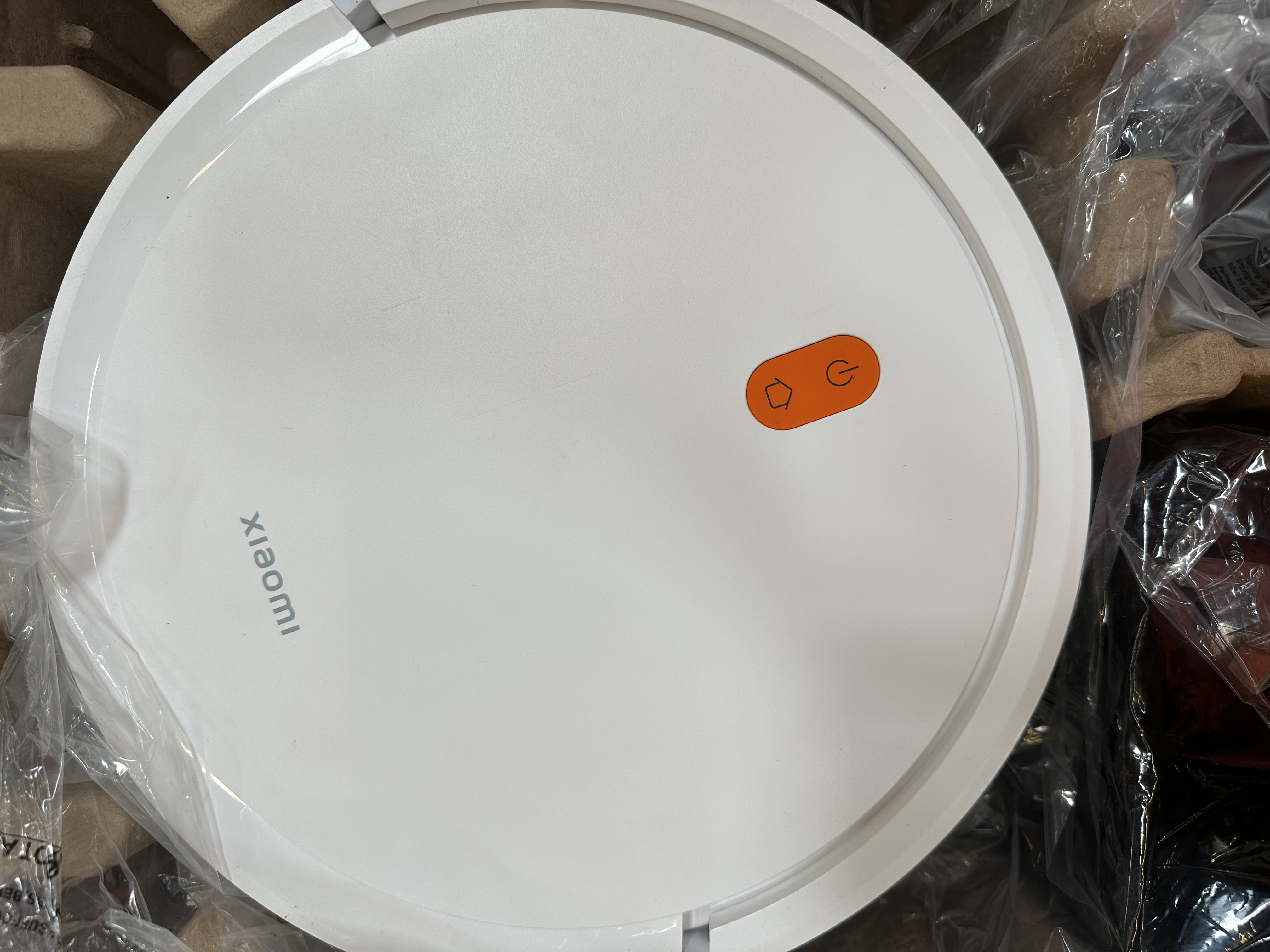 Odkurzacz robot. Odkurzacz jest biały z pomarańczowymi przyciskami.