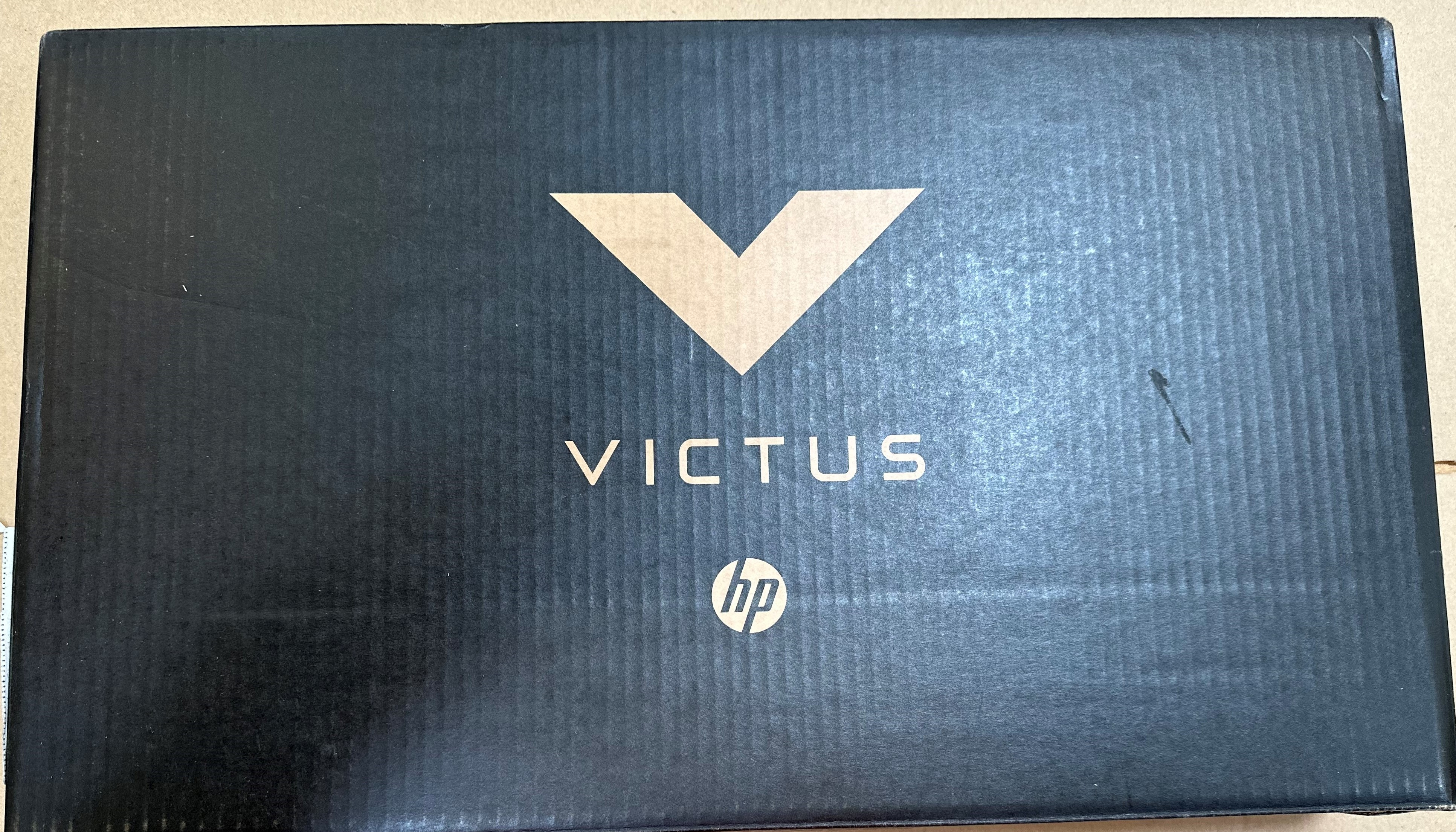 Górna część czarnego pudełka po laptopie z logo VICTUS i HP.