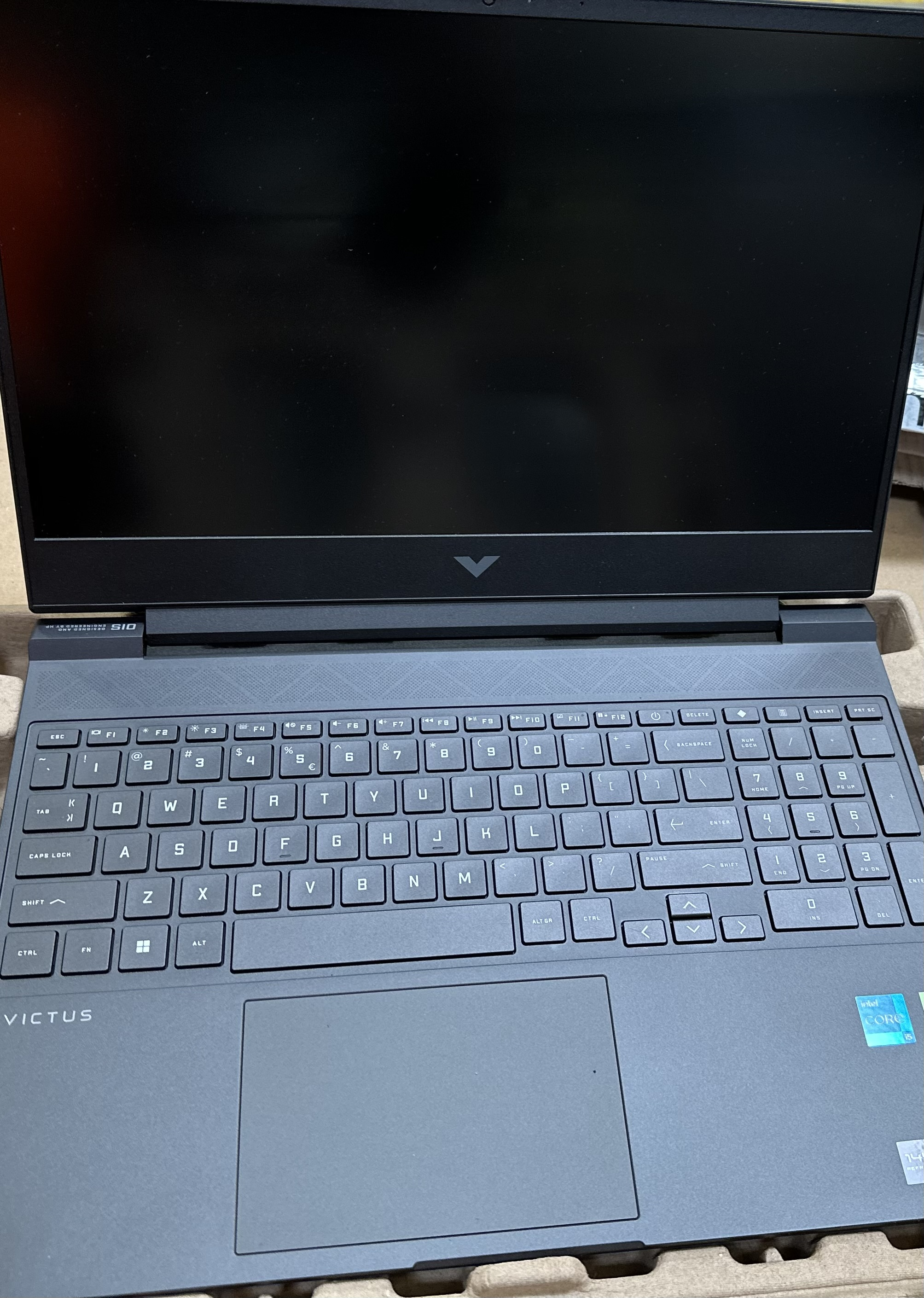 Czarny laptop z otwartym ekranem, pokazujący klawiaturę i gładzik.