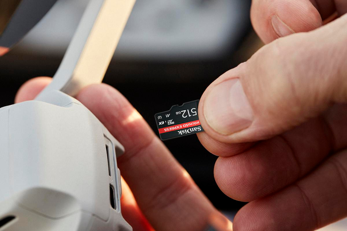 Eine Hand hält eine SanDisk microSD-Karte neben einer Drohne. Die Karte zeigt '512GB'.