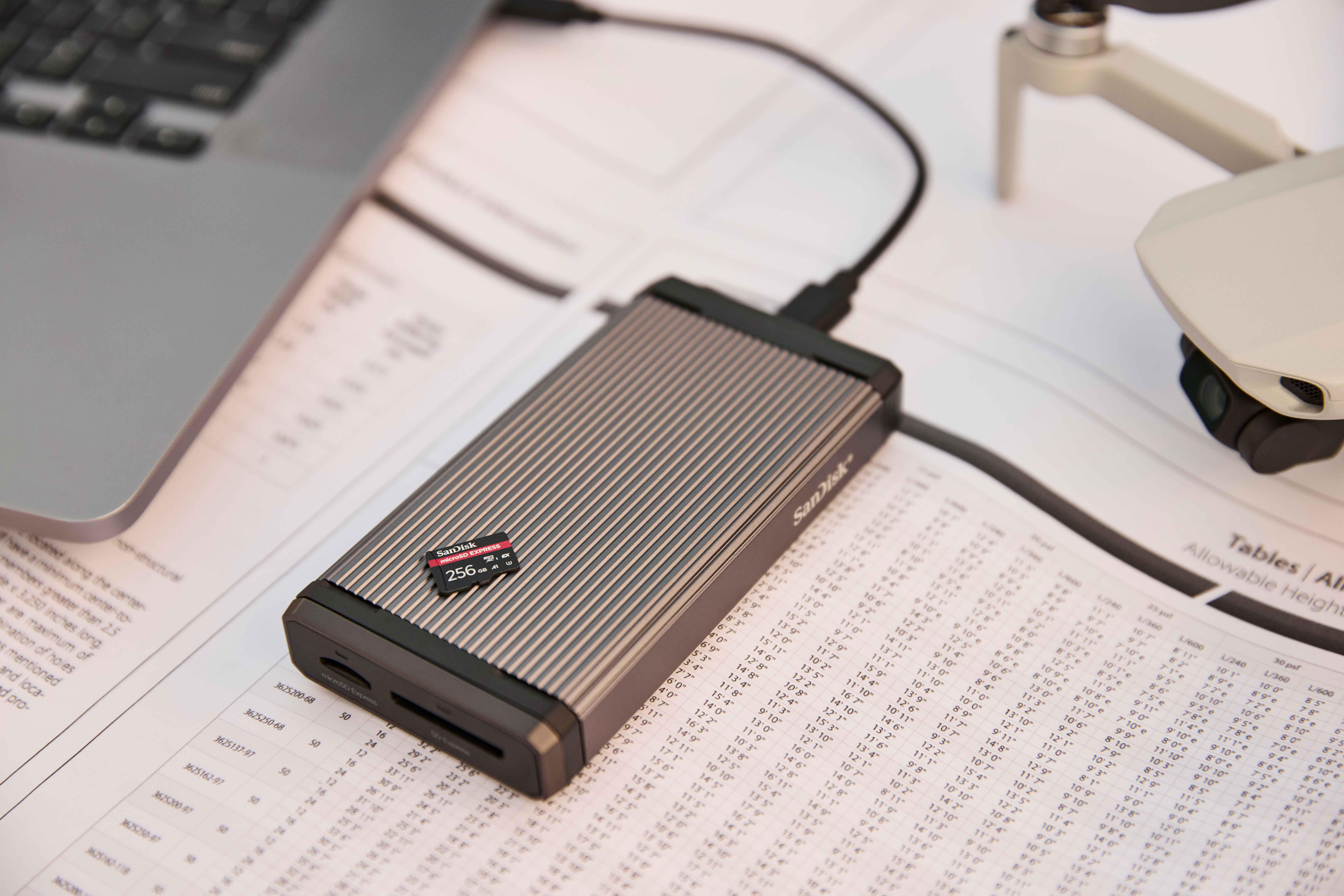 microSD-Karte in Kartenleser, neben Laptop und Drohne auf Tisch.