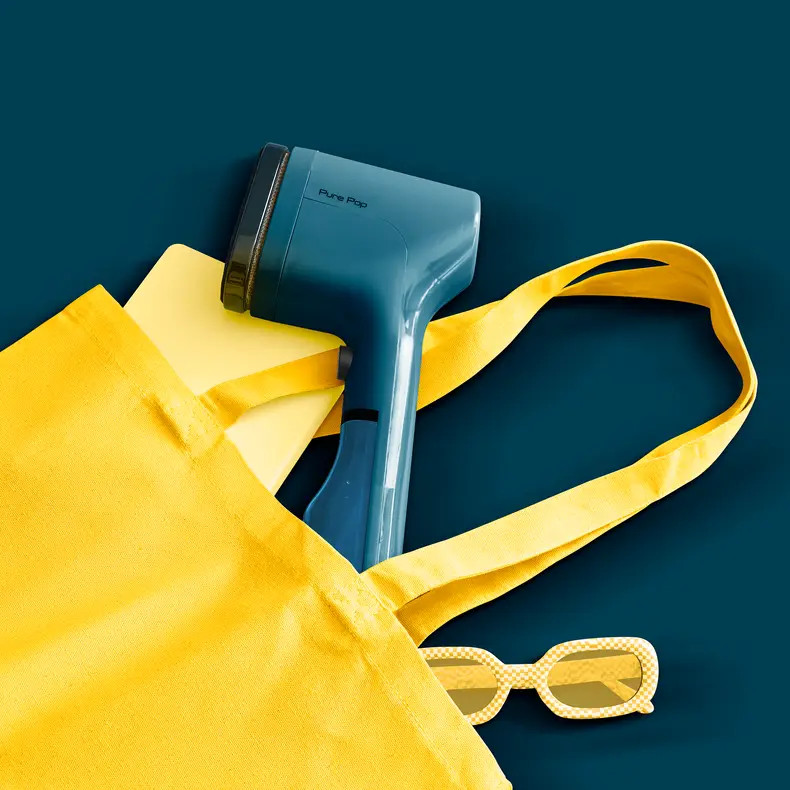 Niebieski parownik do tkanin, żółta torba, okulary na niebieskim tle.