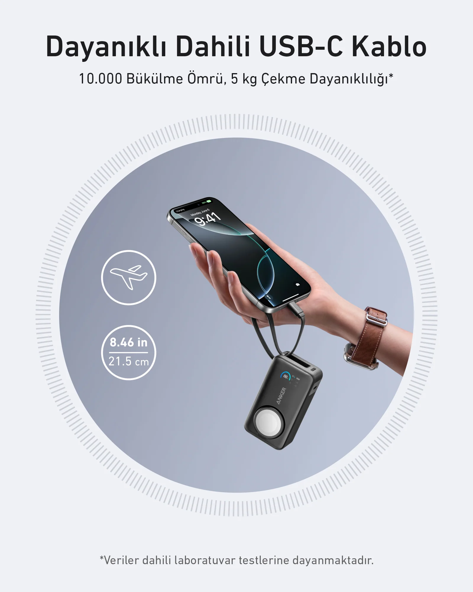 Bir el, bir telefonla birlikte bir şarj cihazı tutuyor. Cihazın bir kablosu var. Gri arka plan.