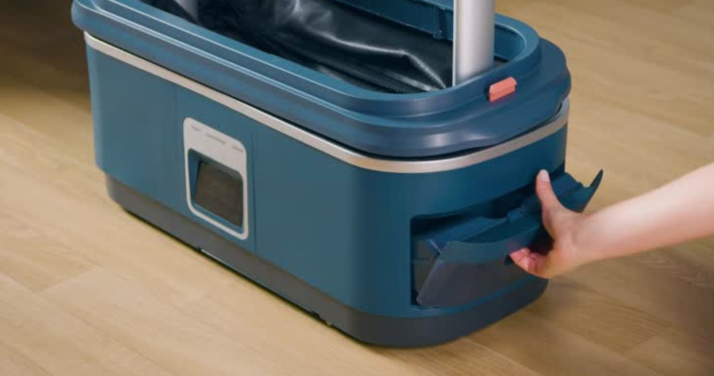 Ręka wysuwa szufladę w kolorze granatowym z granatowej parownicy. Tło: drewniana podłoga.