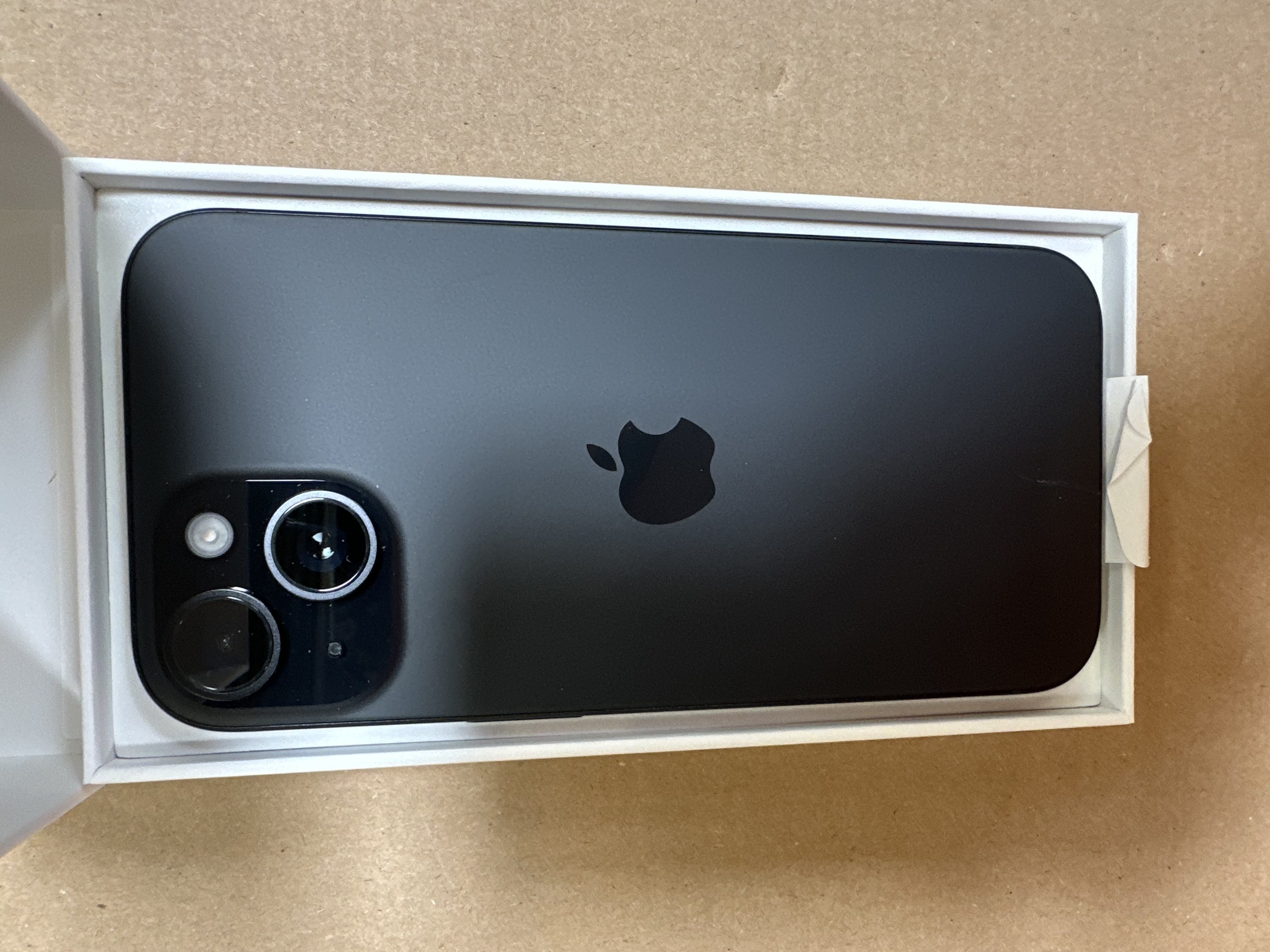 Czarny smartfon z logo Apple w otwartym białym pudełku.