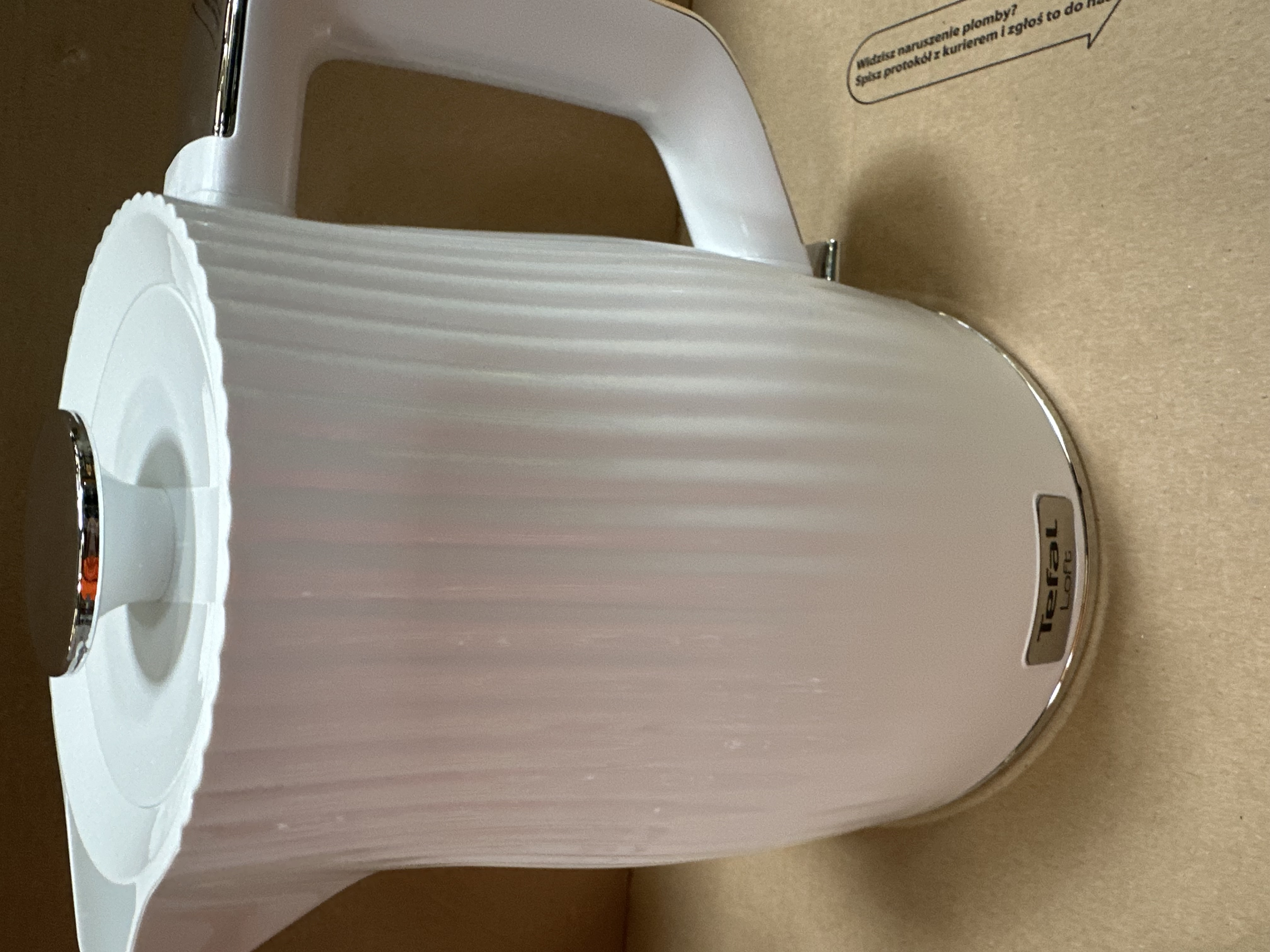 Biały czajnik Tefal Loft. Ma prążkowaną konstrukcję i uchwyt. Znajduje się w pudełku.