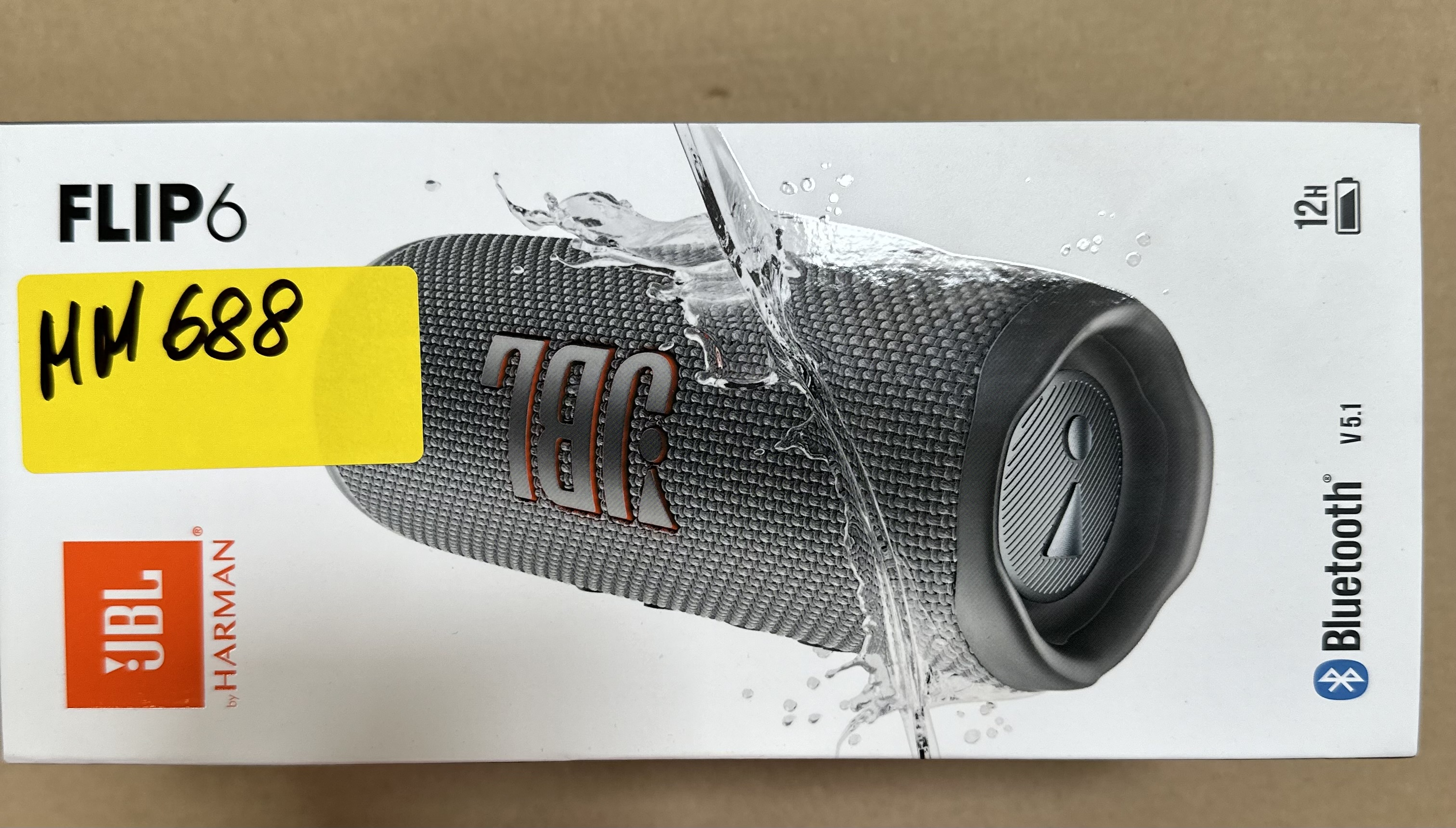 Głośnik JBL Flip 6 w pudełku. Tekst 'FLIP6', '12H' i 'Bluetooth'.
