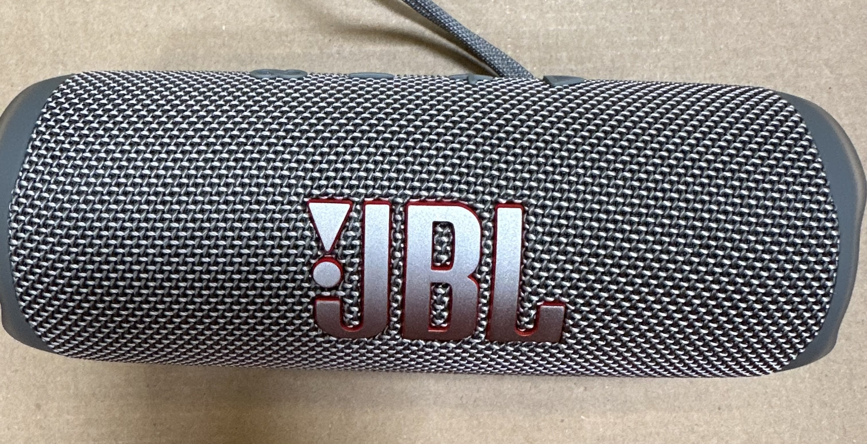 Zbliżenie głośnika JBL Flip 6. Czarno-szary wzór z logo JBL.