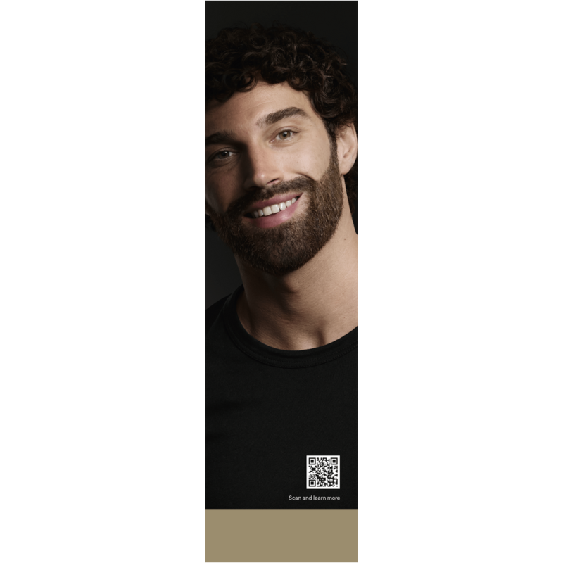 Un hombre sonríe, con barba oscura. Fondo oscuro. Código QR abajo, con 'Scan and learn more'.