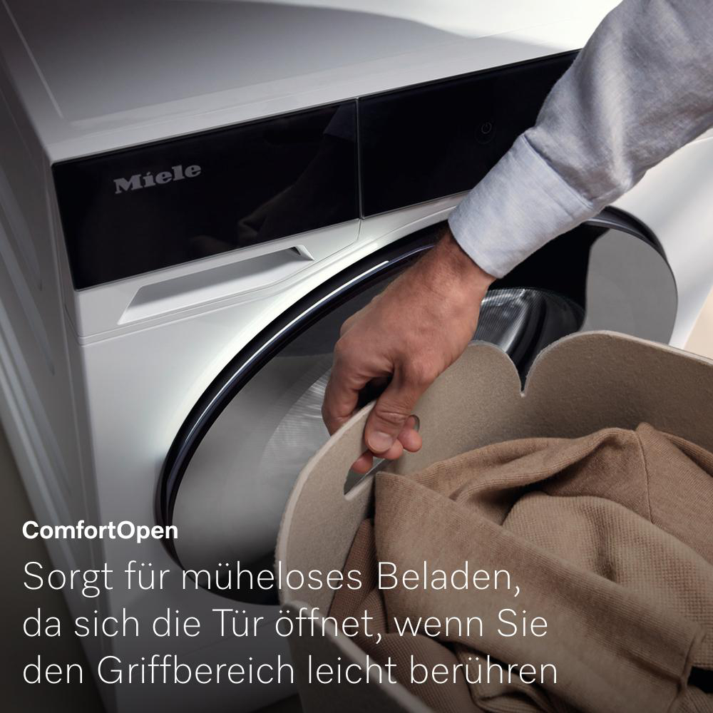 Eine Person öffnet die Waschmaschinentür und zeigt Kleidung in einem beigen Korb.