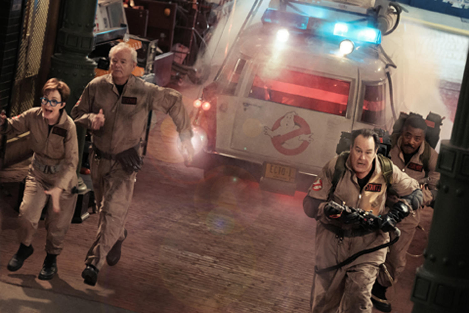 Ghostbusters rennen vor einer Explosion davon, Ecto-1-Auto und ein Gebäude im Hintergrund.