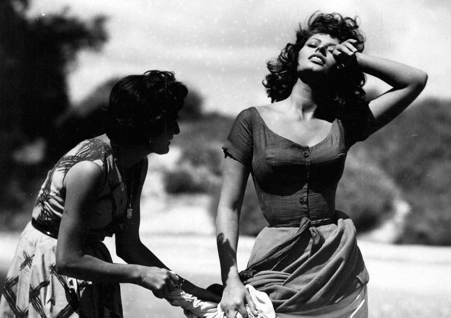 Zwei Frauen in einer sonnigen Szene. Eine hält Wäsche, die andere posiert. Schwarzweißfotografie.