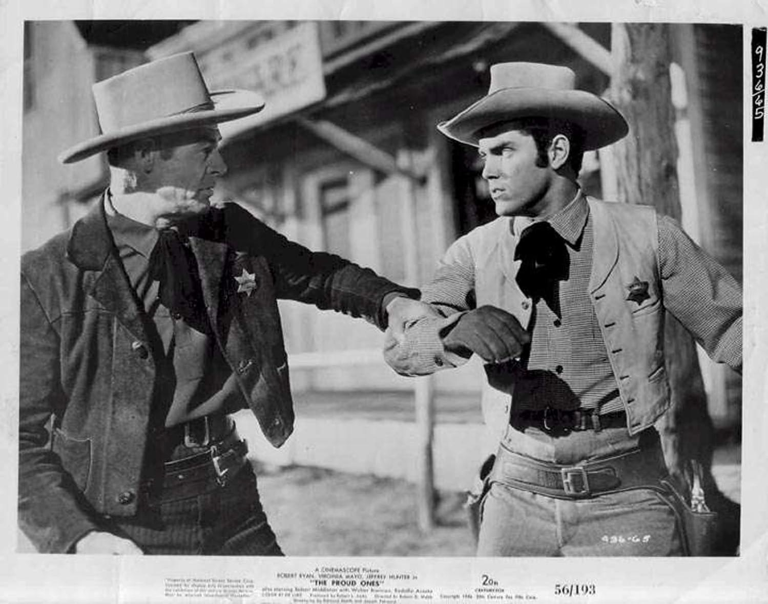 Schwarzweißfoto: Zwei Cowboys stehen sich gegenüber, einer greift aus. Western-Szene, Aufnahme im Freien.
