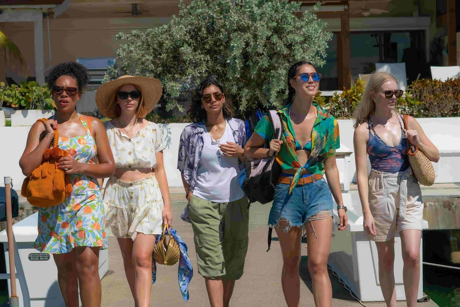 Fünf Frauen gehen zusammen. Sie tragen Sommerkleidung. Sonniger Tag. Hintergrund: Bäume und blauer Himmel.