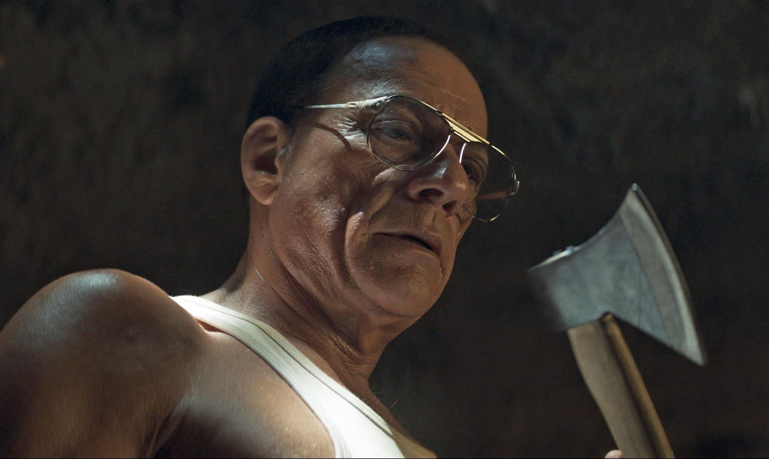 Ein Mann mit Brille hält eine Axt mit dunklem Hintergrund.