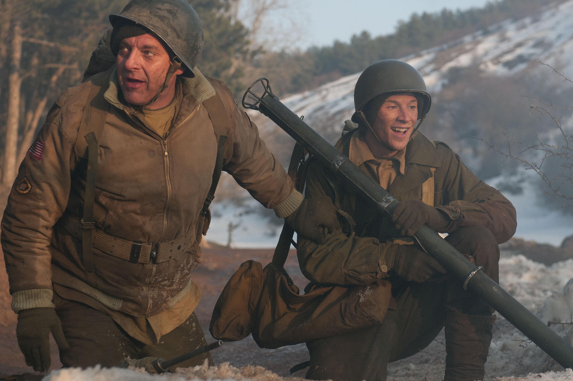 Zwei Soldaten in Winterausrüstung, einer zeigt, der andere lächelt.