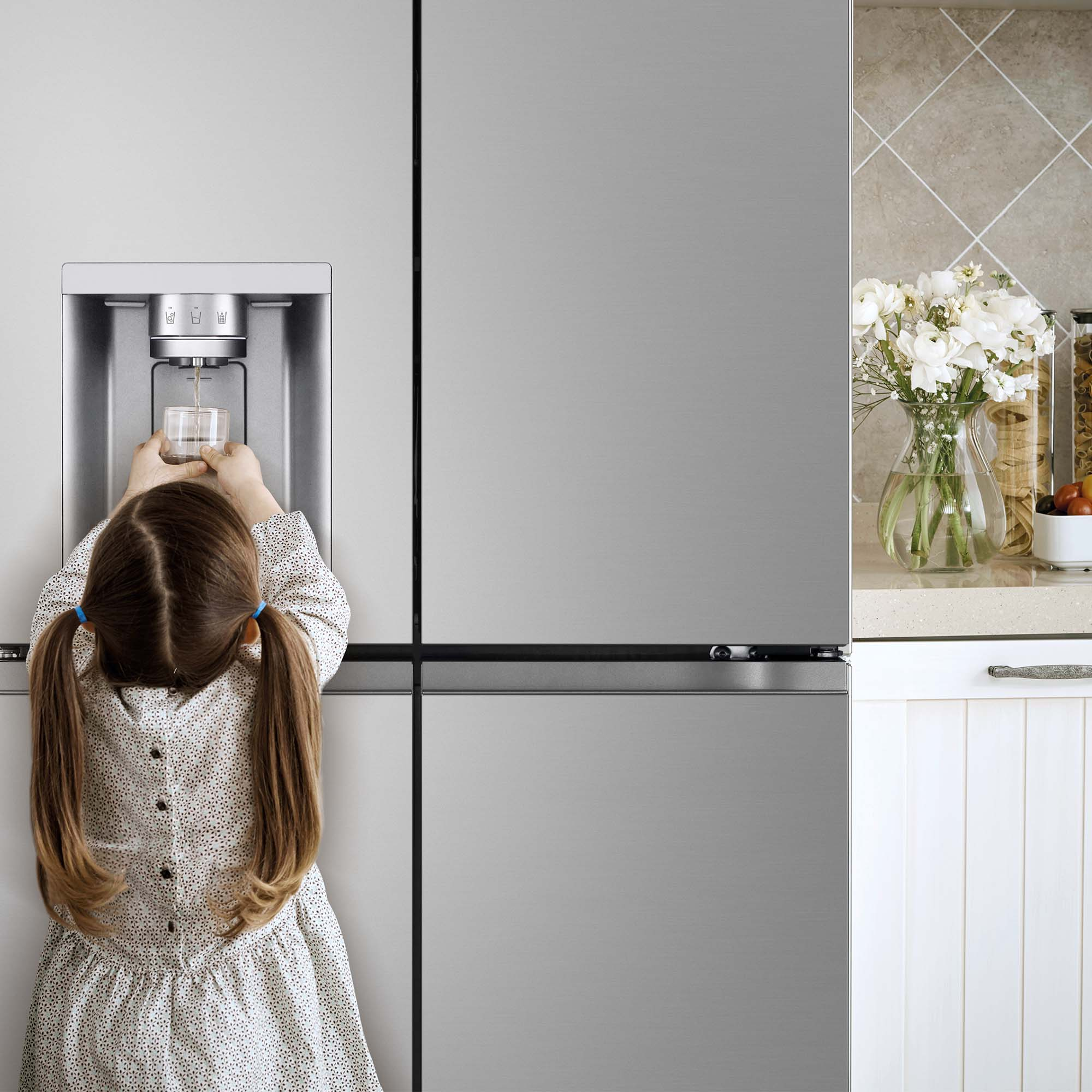 Una niña en un refrigerador. Está obteniendo agua.