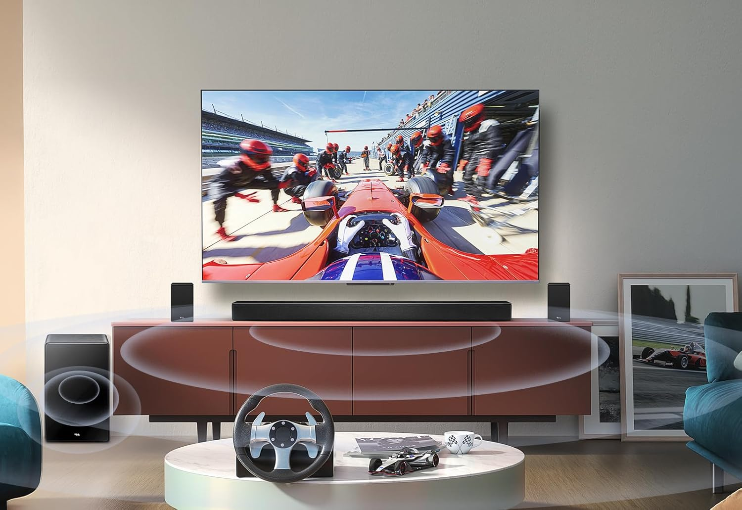 Un televisor muestra una carrera, con barra de sonido, altavoces y un volante sobre una mesa.