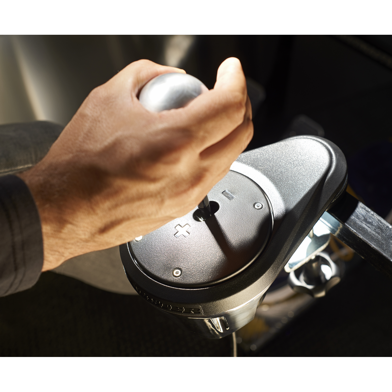 Hand on a black control panel, with a silver lever. Focus on hand and lever.