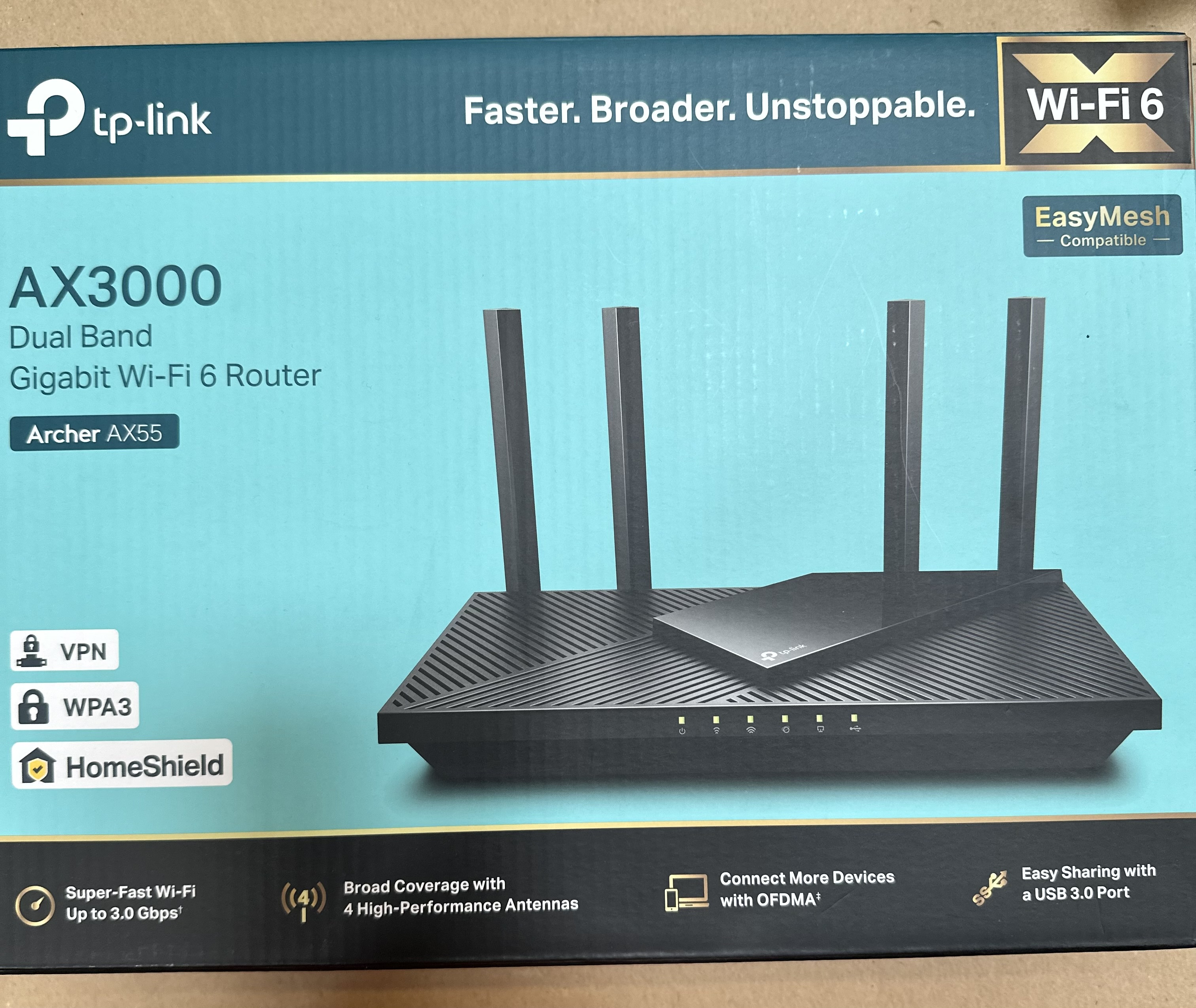 Router TP-Link Wi-Fi 6. Pudełko jest niebiesko-czarne. Router ma 4 anteny.