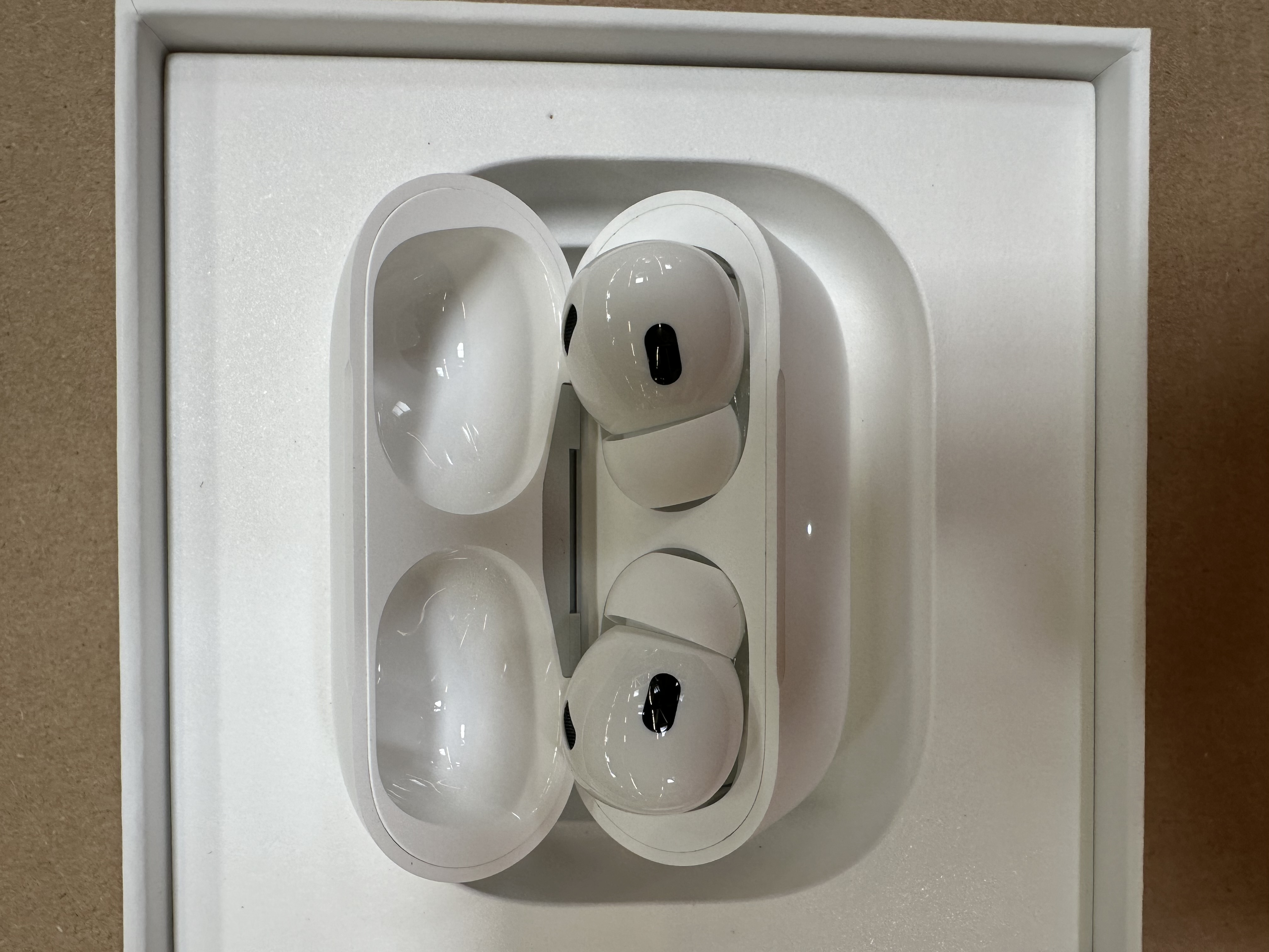 Białe AirPods Pro w etui ładującym. Etui otwarte, ukazujące słuchawki.