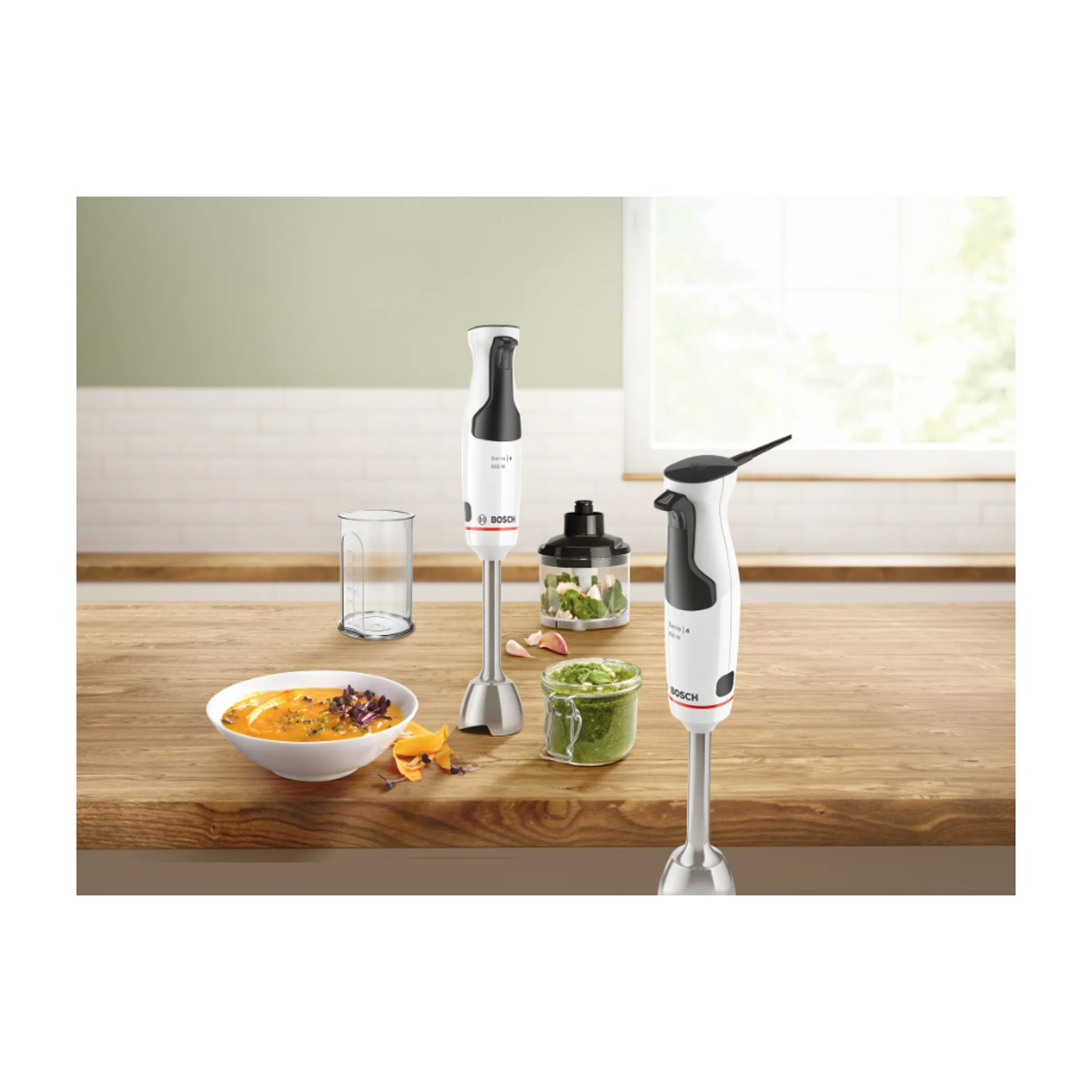 Frullatori a immersione e accessori: una ciotola di zuppa, ingredienti e due frullatori su legno.