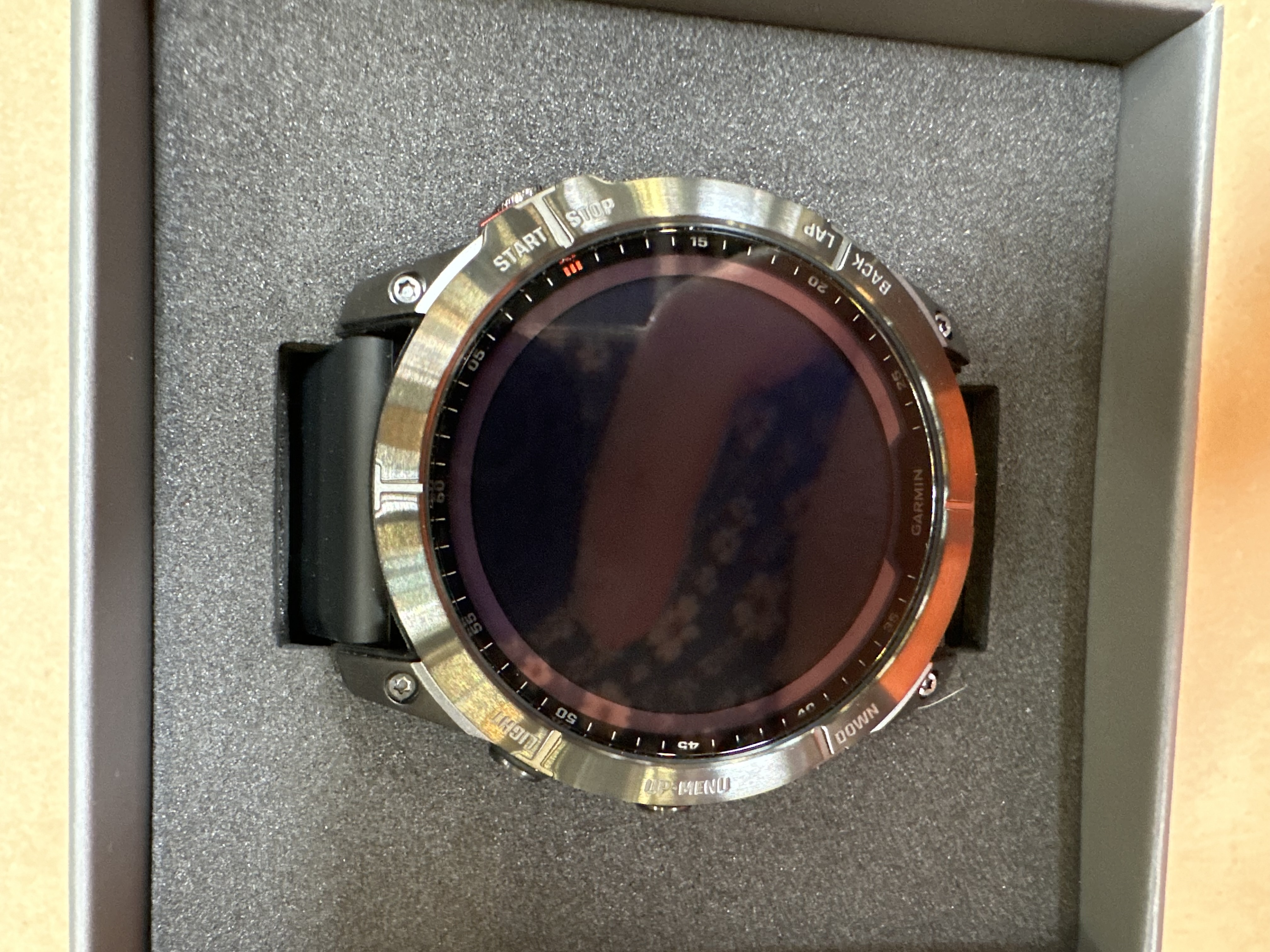 Zegarek Garmin w pudełku, ukazujący tarczę i pasek.