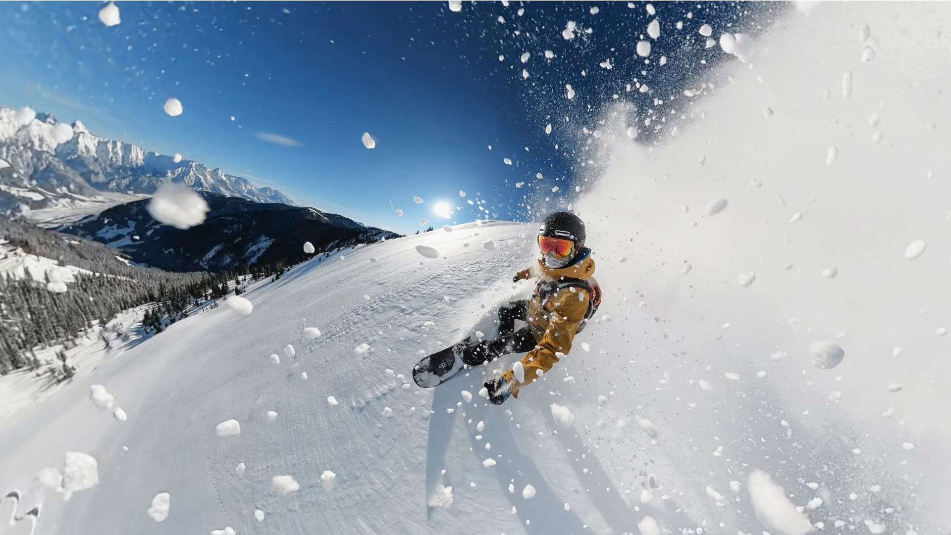 Snowboardos havas lejtőn, hóval a levegőben.