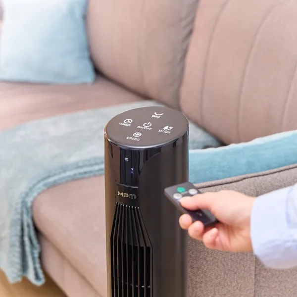 Czarny wentylator wieżowy jest sterowany przez osobę za pomocą pilota.