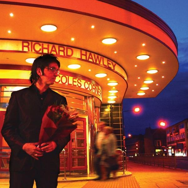 Mann mit Blumen steht vor einem Theater. Schild liest sich 'Richard Hawley Coles Corner'.