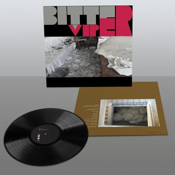 Albumcover mit Bild eines zerstörten Speisesaals, Vinylplatte im Vordergrund und Albumcover.