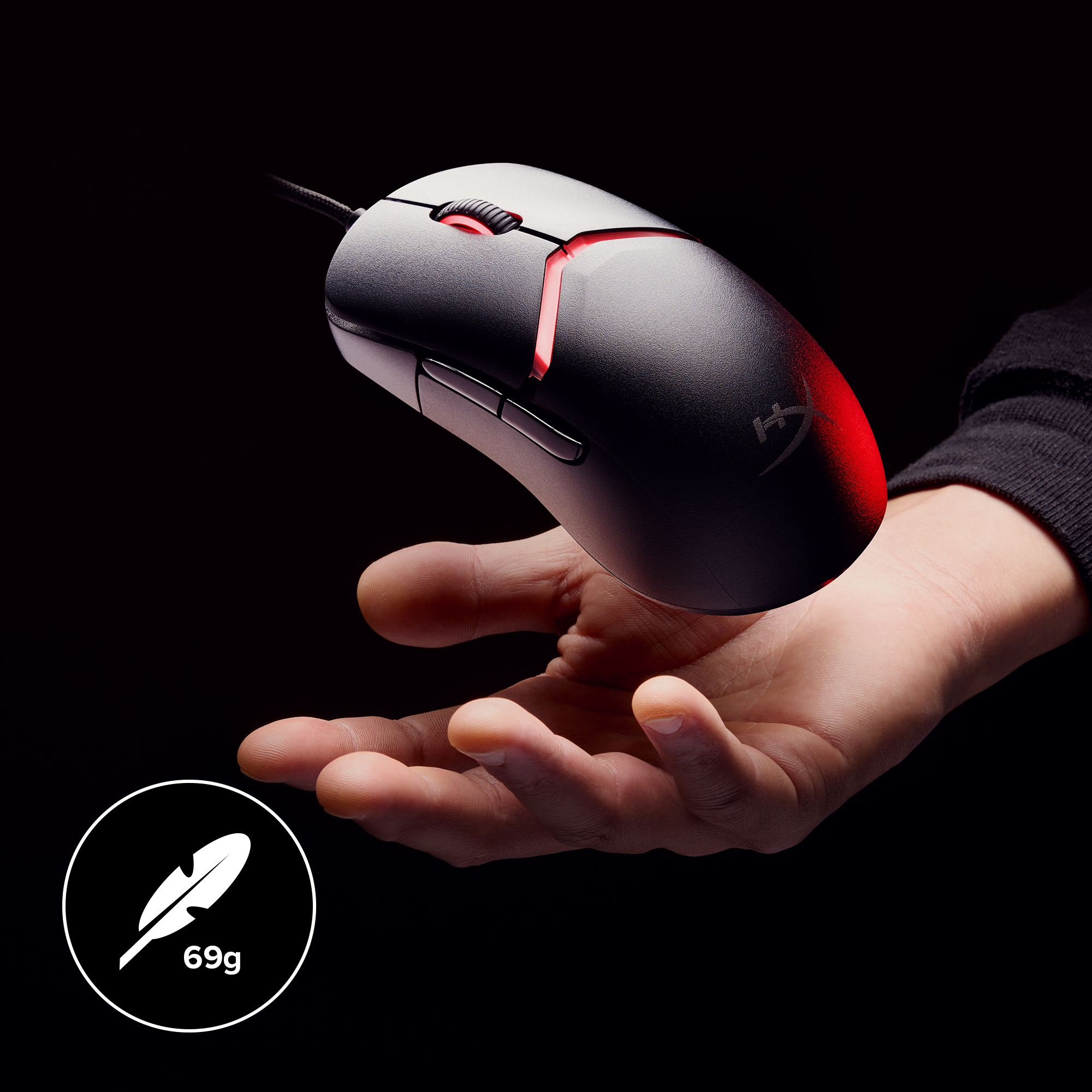 Hand holding black computer mouse with red lighting. Black background.